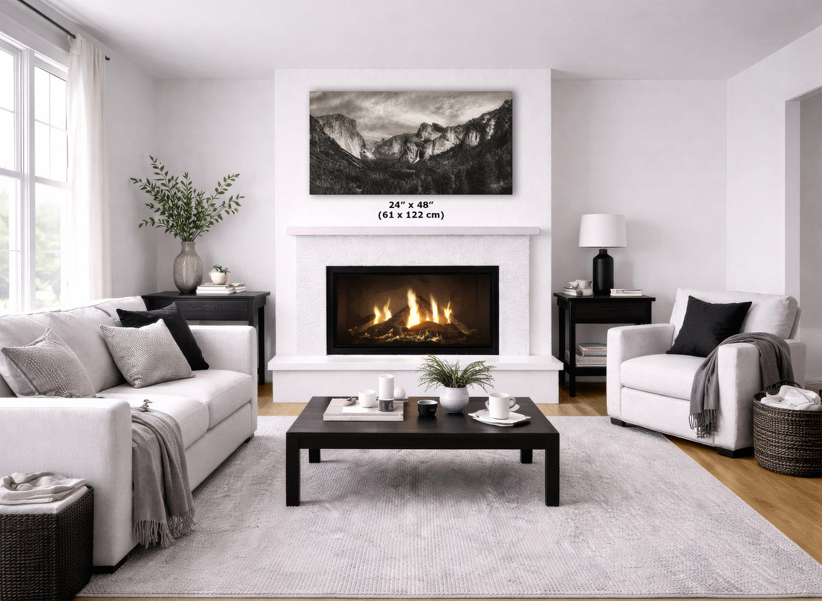 A black and white mountain landscape wall art print displayed above a white fireplace in a modern, bright living room. The dimensions '24" x 48" (61 x 122 cm)' are overlaid on the print.