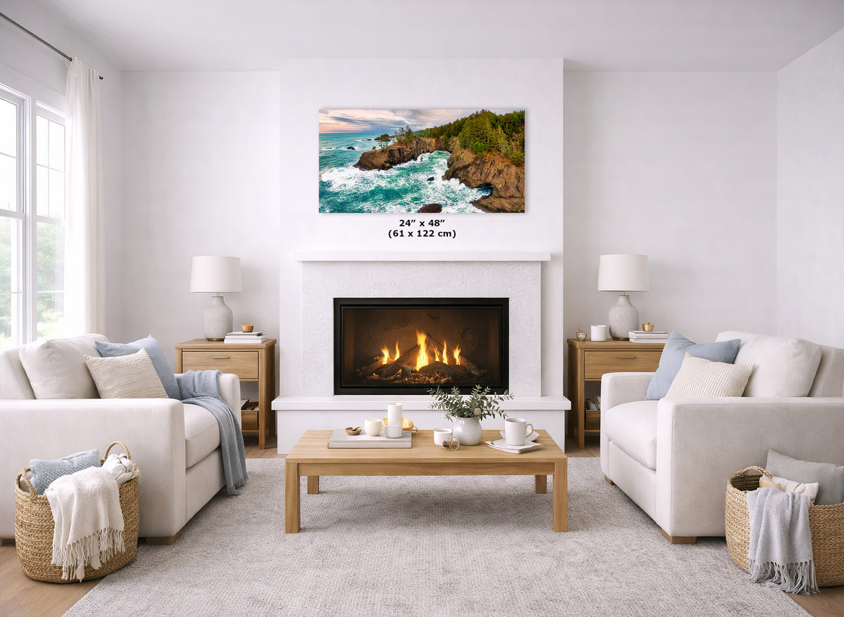 A coastal landscape wall art print hangs above a fireplace in a bright, modern living room. The print shows rocky shoreline waves with green cliffs and a sunset sky.