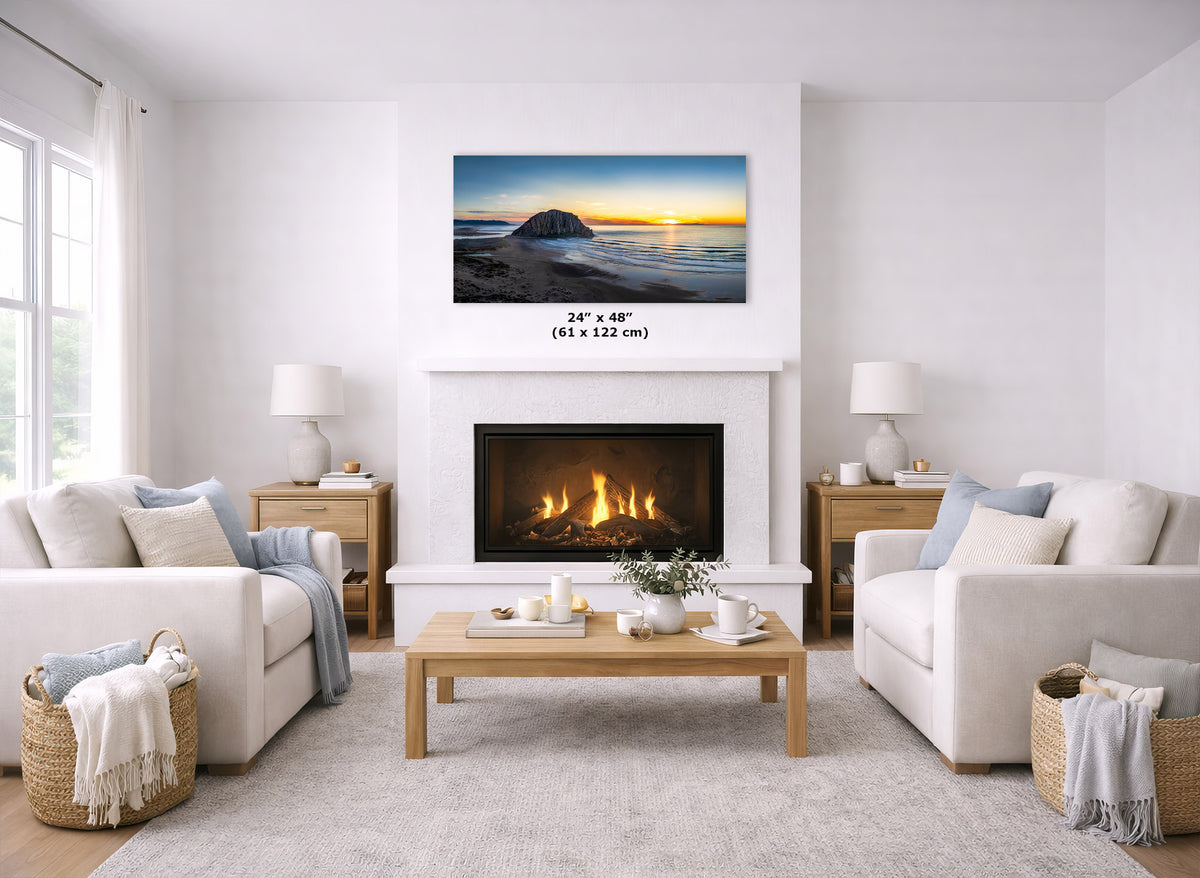 A wall art print showing a beach sunset is displayed above a fireplace in a bright, modern living room. The print includes a size marker reading 24" x 48" (61 x 122 cm).