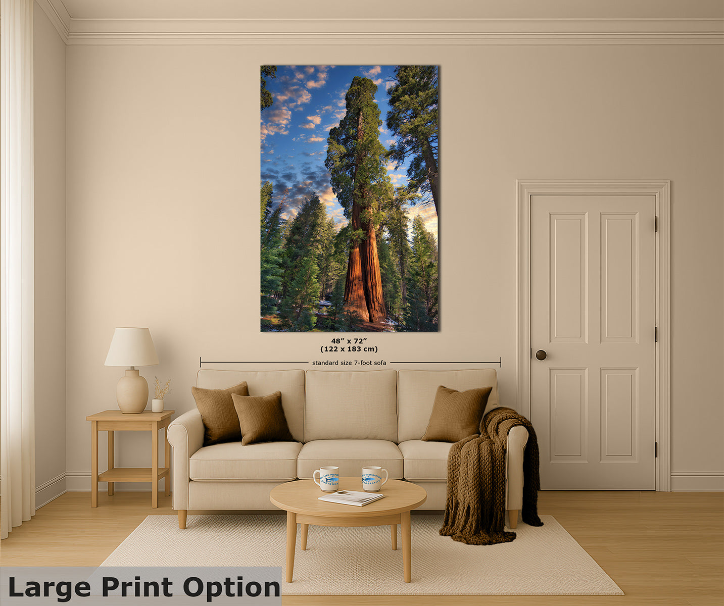 A large vertical wall art print showing a forest scene with a giant sequoia tree, displayed above a beige sofa in a styled living room.