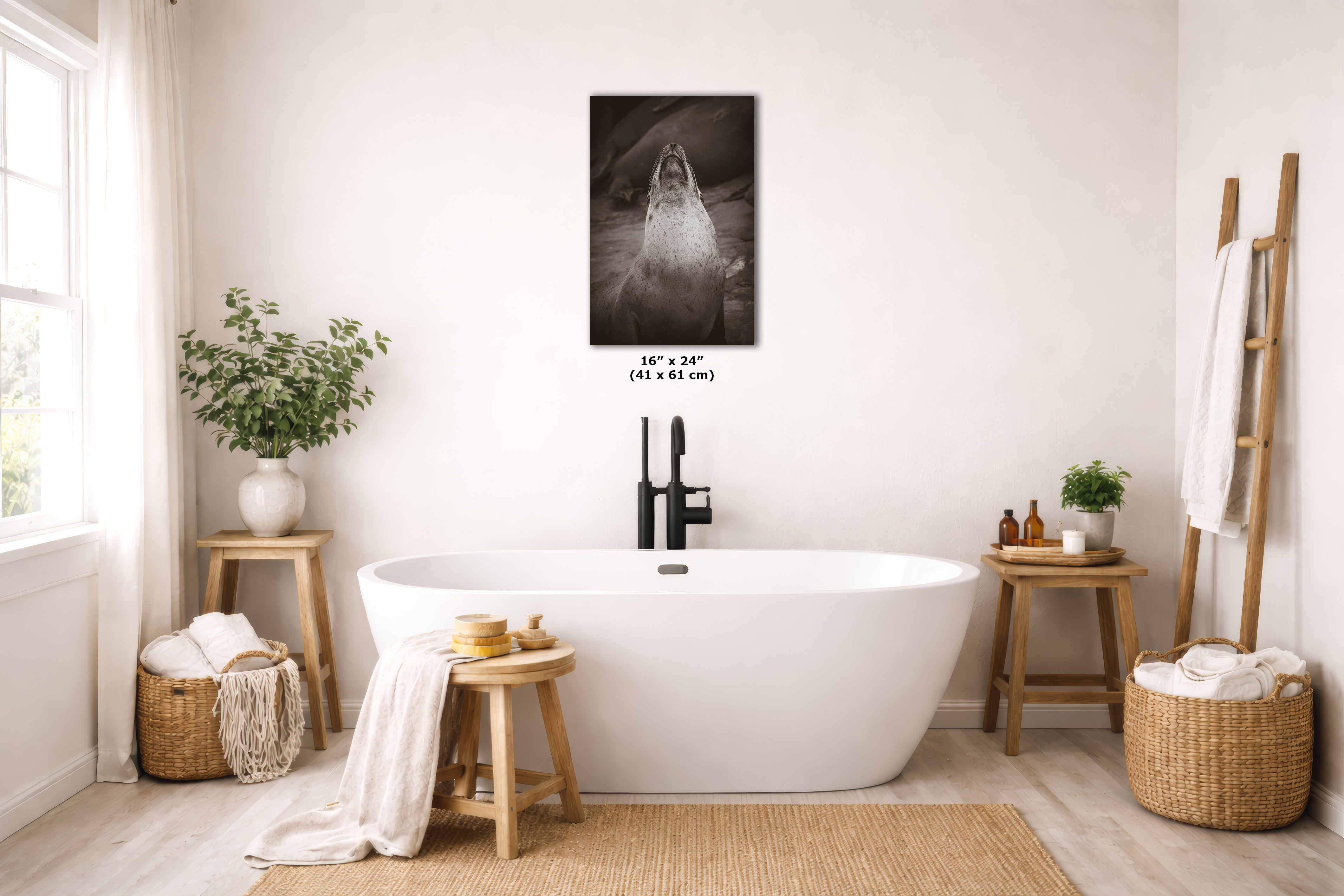 A freestanding white bathtub in a bright, neutral-toned bathroom with a black-and-white shark wall art print centered above it. The room includes wooden stools, woven baskets, plants, and a ladder-style towel rack.