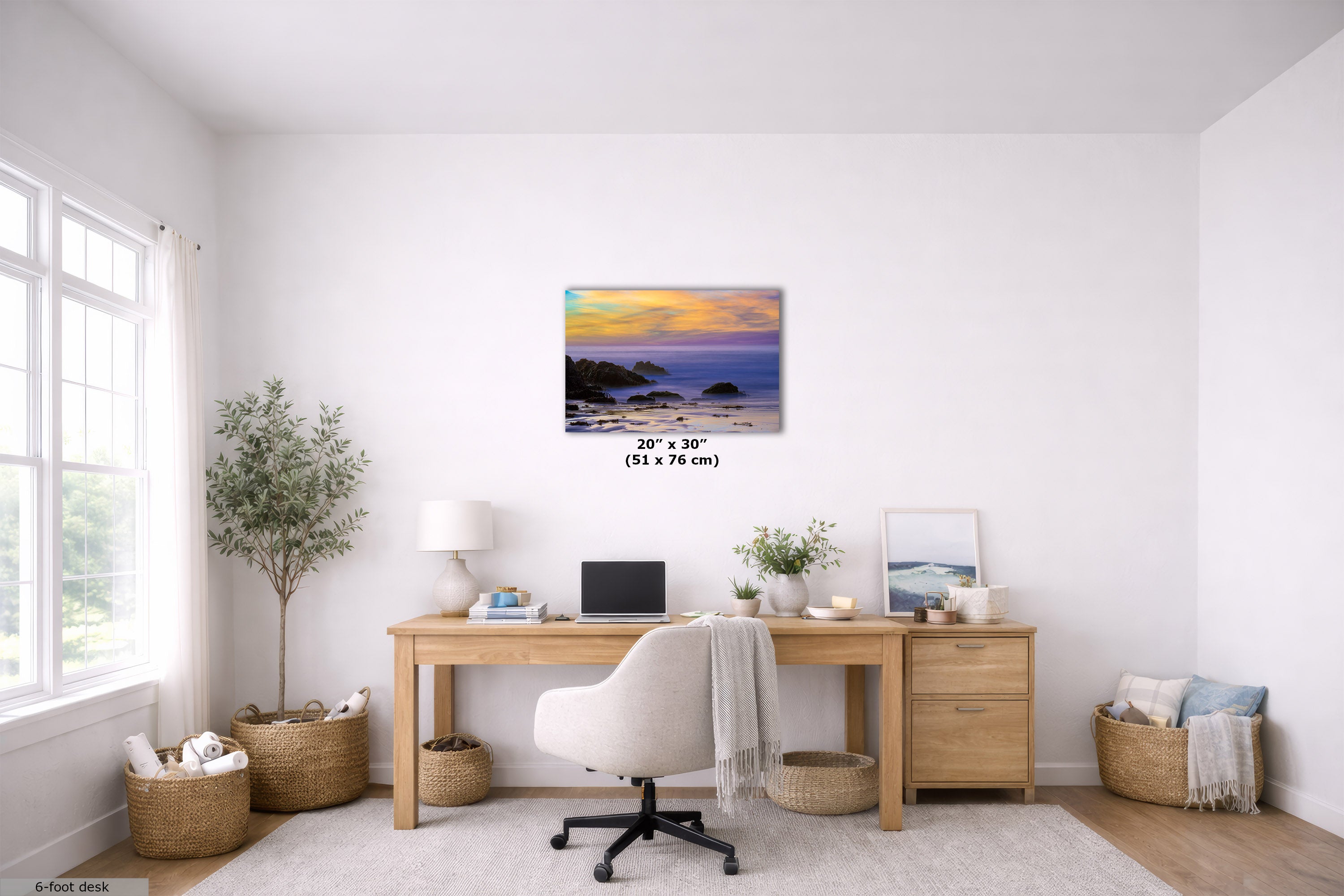 A 20" x 30" canvas print of a sunset beach scene is displayed on a white wall in a modern, bright home office setting with a wooden desk, white chair, and plants.