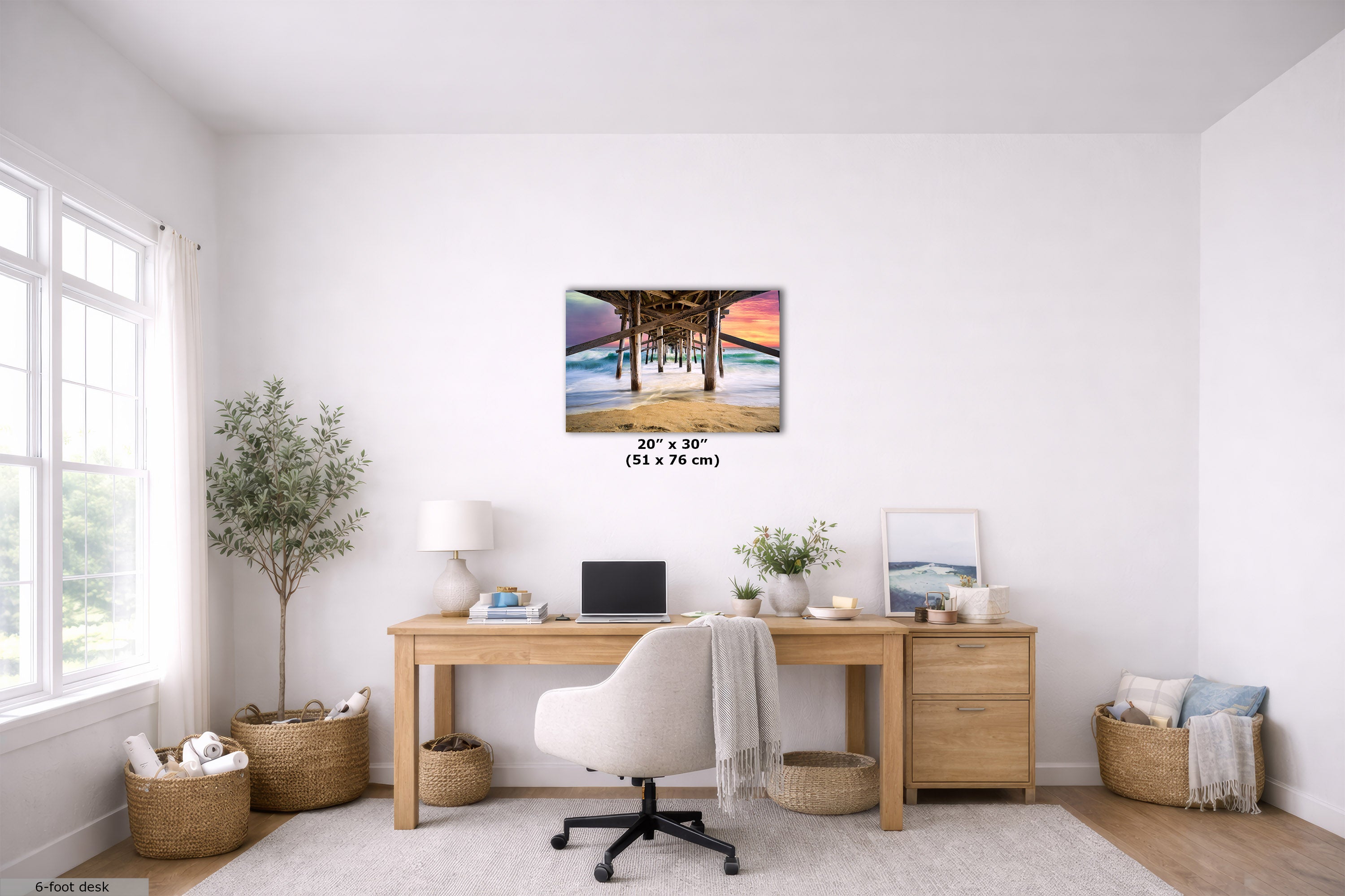 A 20" x 30" wall art print depicting a tropical beach scene under a palm tree, displayed in a bright, modern home office setting above a wooden desk.