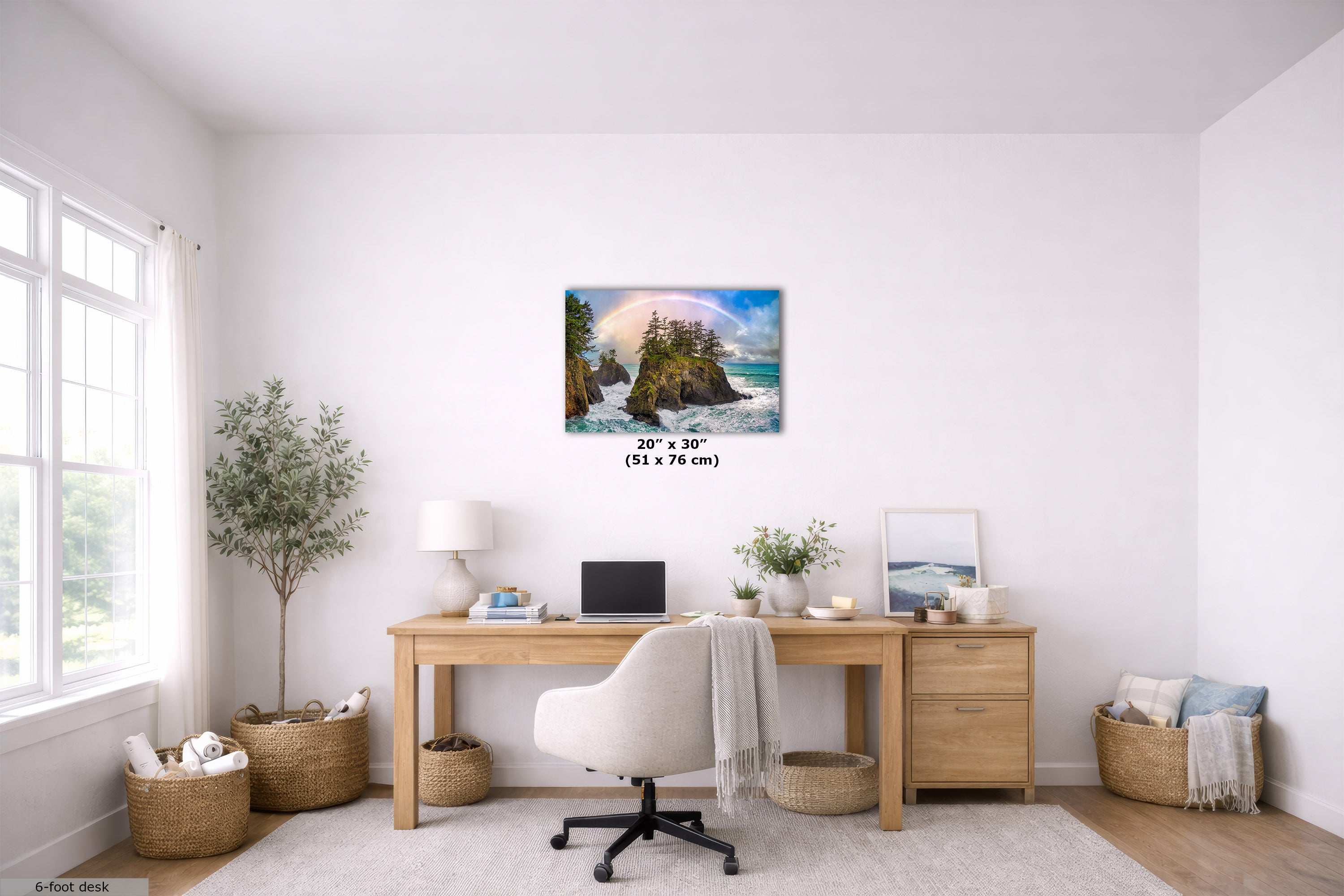 A 20" x 30" canvas print of a coastal landscape with a rainbow over a rocky island is displayed on a white wall in a bright, modern home office setting with a wooden desk, white chair, and plants.