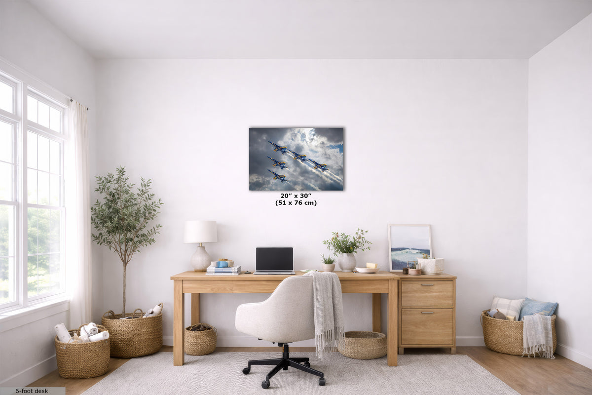 A wall art print depicting a scenic bridge over water under a dramatic sunset sky, displayed in a bright, modern home office setting above a wooden desk with a white office chair.