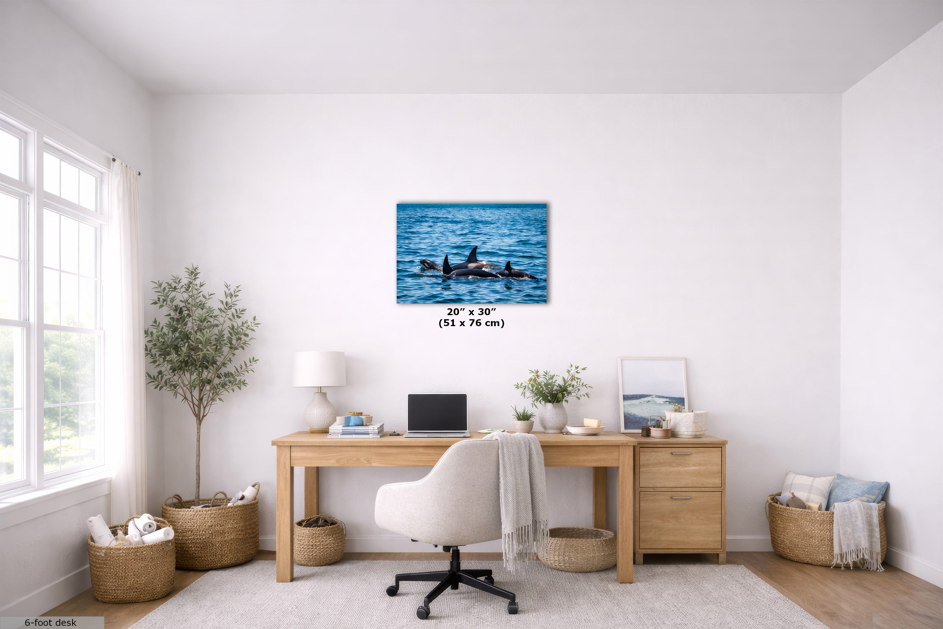 A wall art print showing an orca family in blue ocean water, displayed above a wooden desk in a bright, modern home office. The print includes size text indicating 20" x 30" (51 x 76 cm).