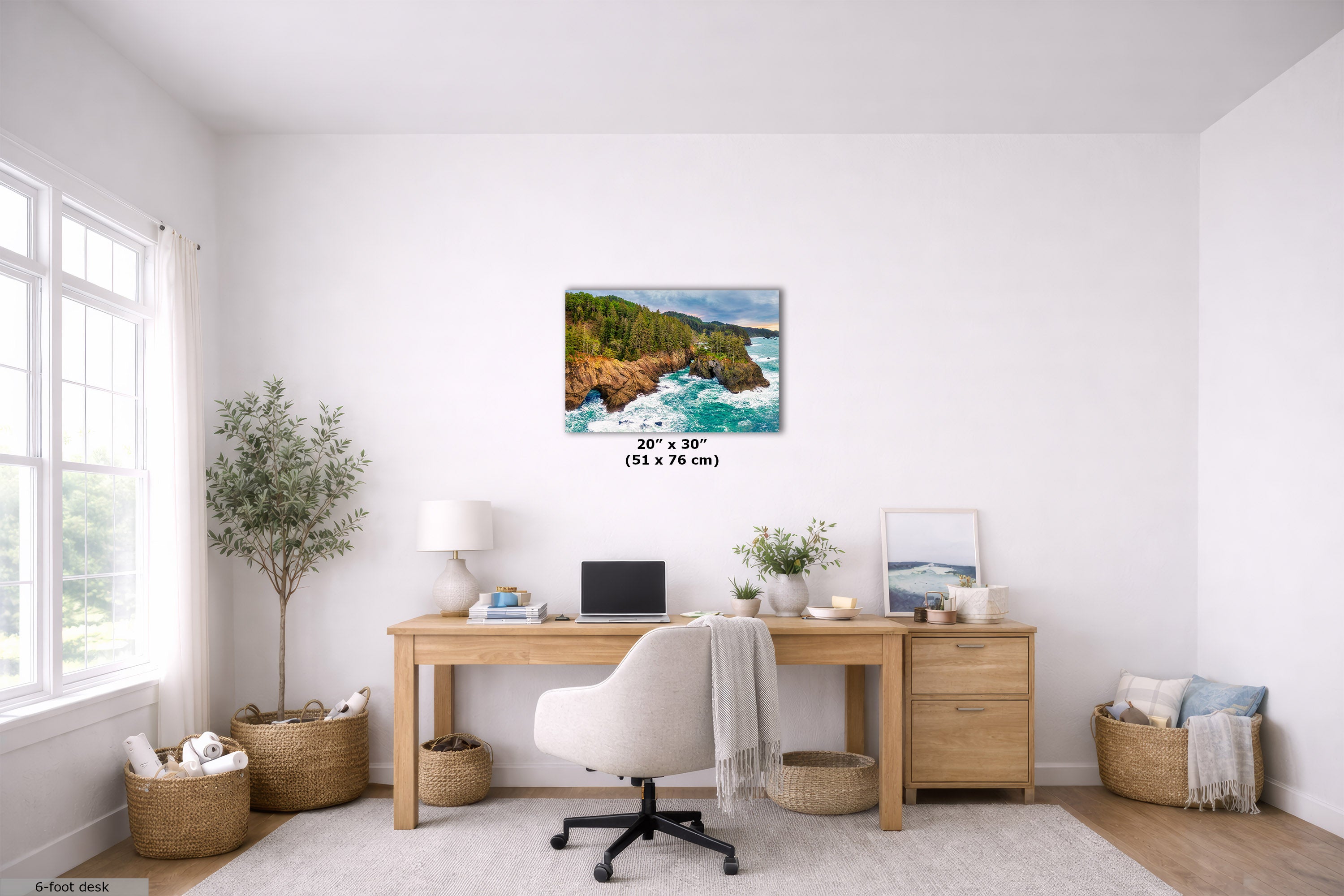 A coastal landscape wall art print displayed above a wooden desk in a bright, modern home office. The print depicts green cliffs and blue ocean waves, with dimensions labeled as 20" x 30" (51 x 76 cm) below it.