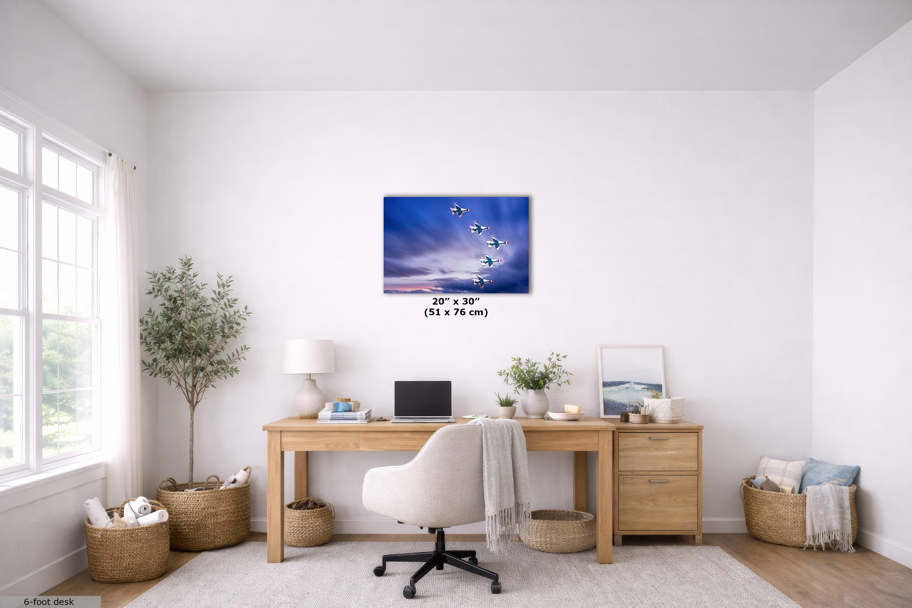 A 20x30-inch canvas print depicting a flock of white geese flying against a blue sky with clouds, displayed on a white wall in a modern, bright home office setting above a wooden desk.