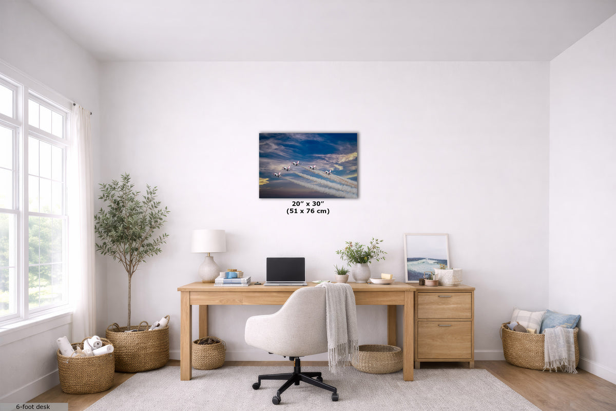 A 20x30 inch canvas print of a snowy mountain landscape under a blue sky, displayed on a white wall in a modern, bright home office setting above a wooden desk.