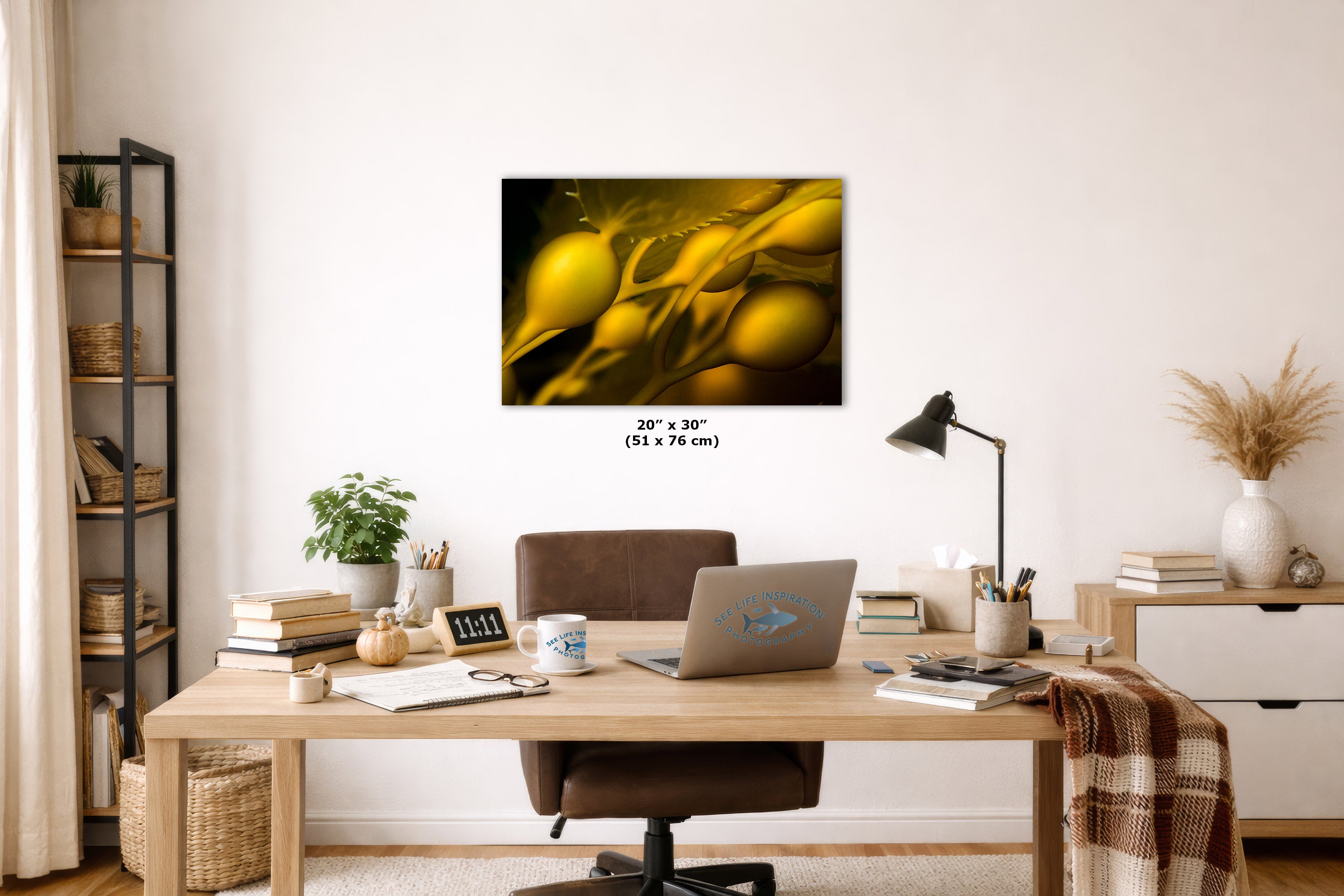 A wall art print featuring a close-up abstract yellow and gold underwater design, displayed above a wooden desk in a styled home office setting. The print includes size text reading 20 x 30" (51 x 76 cm) below it.