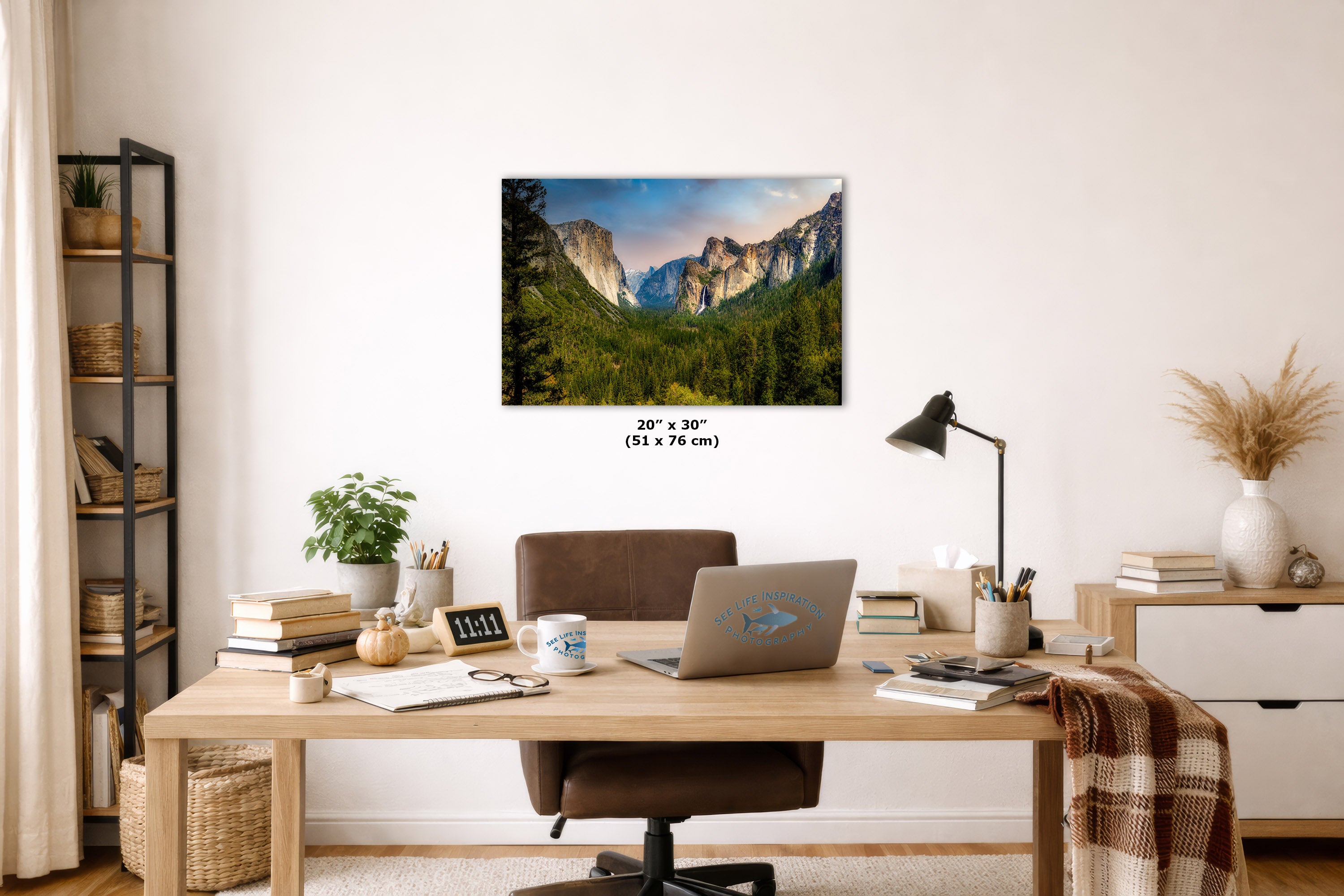 A wall art print showing a mountain valley landscape hangs above a wooden desk in a styled home office. The print is labeled 20 x 30 inches (51 x 76 cm).