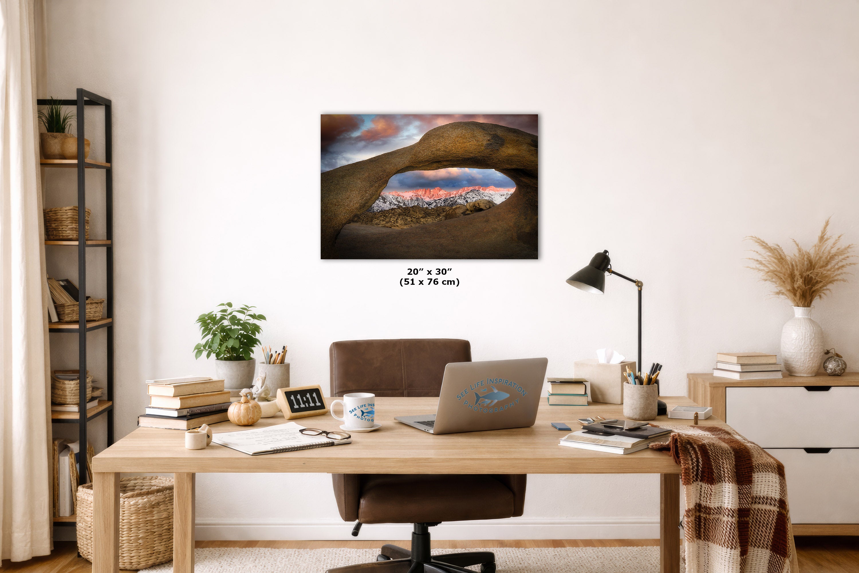 Home office with a desk, laptop, and decorative items, featuring a large wall art print.