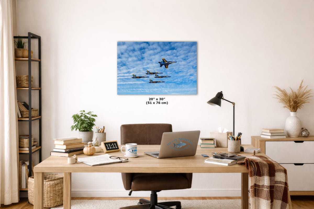 A square wall art print showing fighter jets flying in a blue sky with clouds, displayed above a wooden desk in a styled home office setting. The print includes size text indicating 20 x 30 inches.