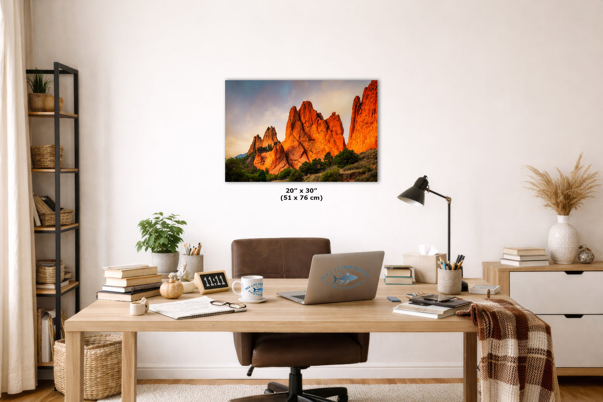 A wall art print showing a desert rock landscape with orange cliffs and blue sky, displayed above a wooden desk in a styled home office. The print includes size text reading 20 x 30 inches (51 x 76 cm).