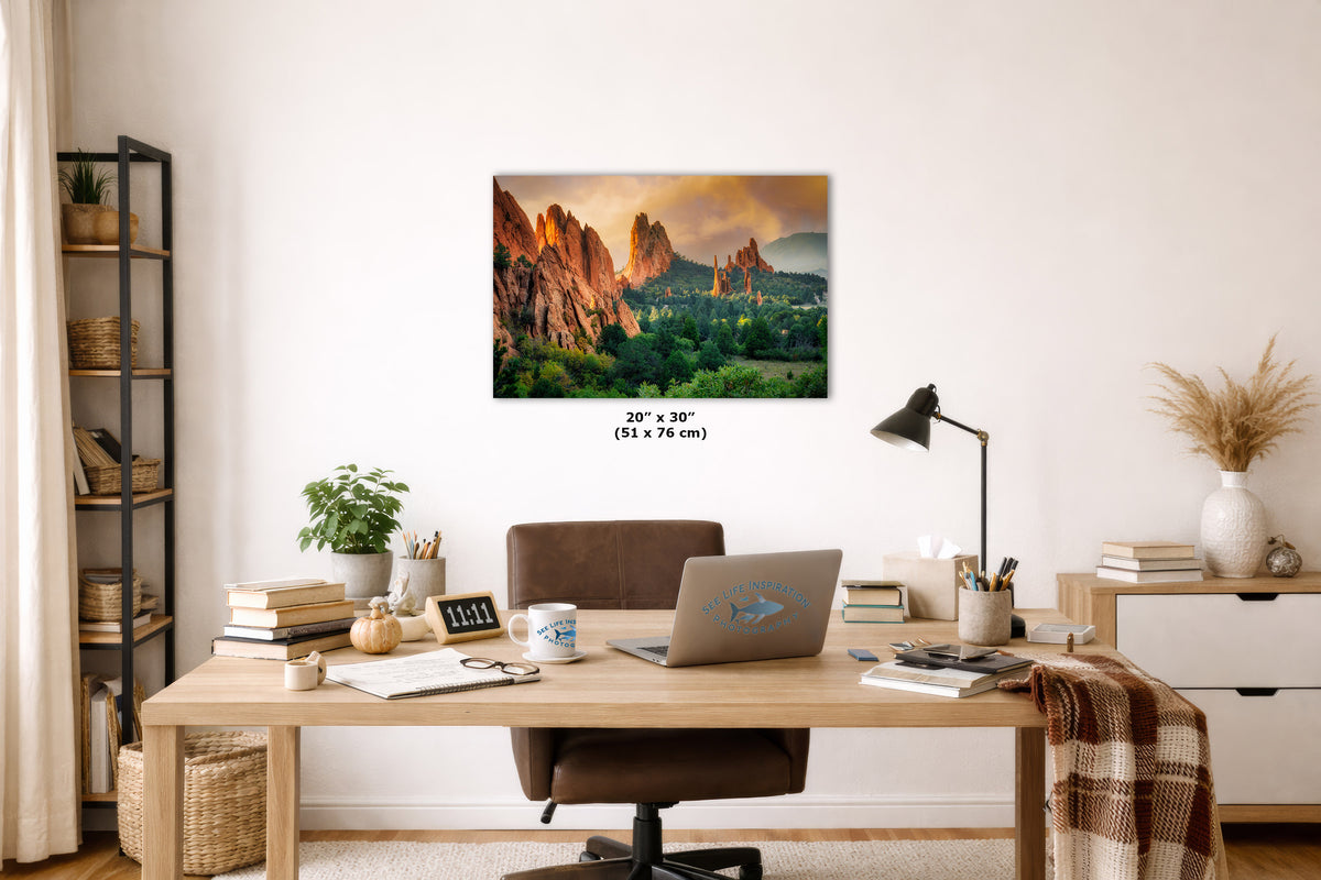 A wall art print depicting a colorful desert canyon landscape at sunset, displayed on a white wall above a wooden desk in a styled home office setting.