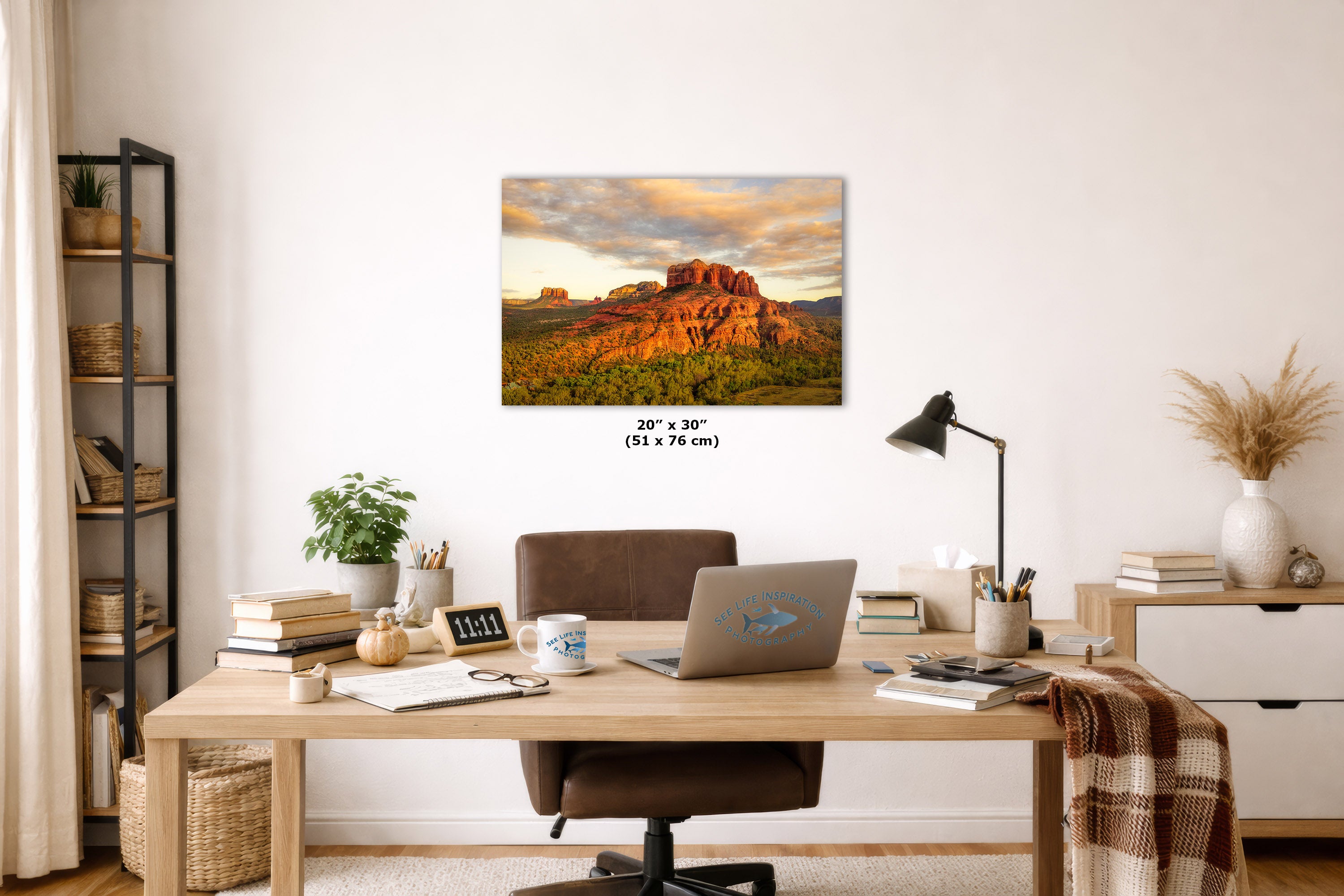 Home office with a desk, laptop, and decorative items, featuring a large wall art print of a desert landscape.