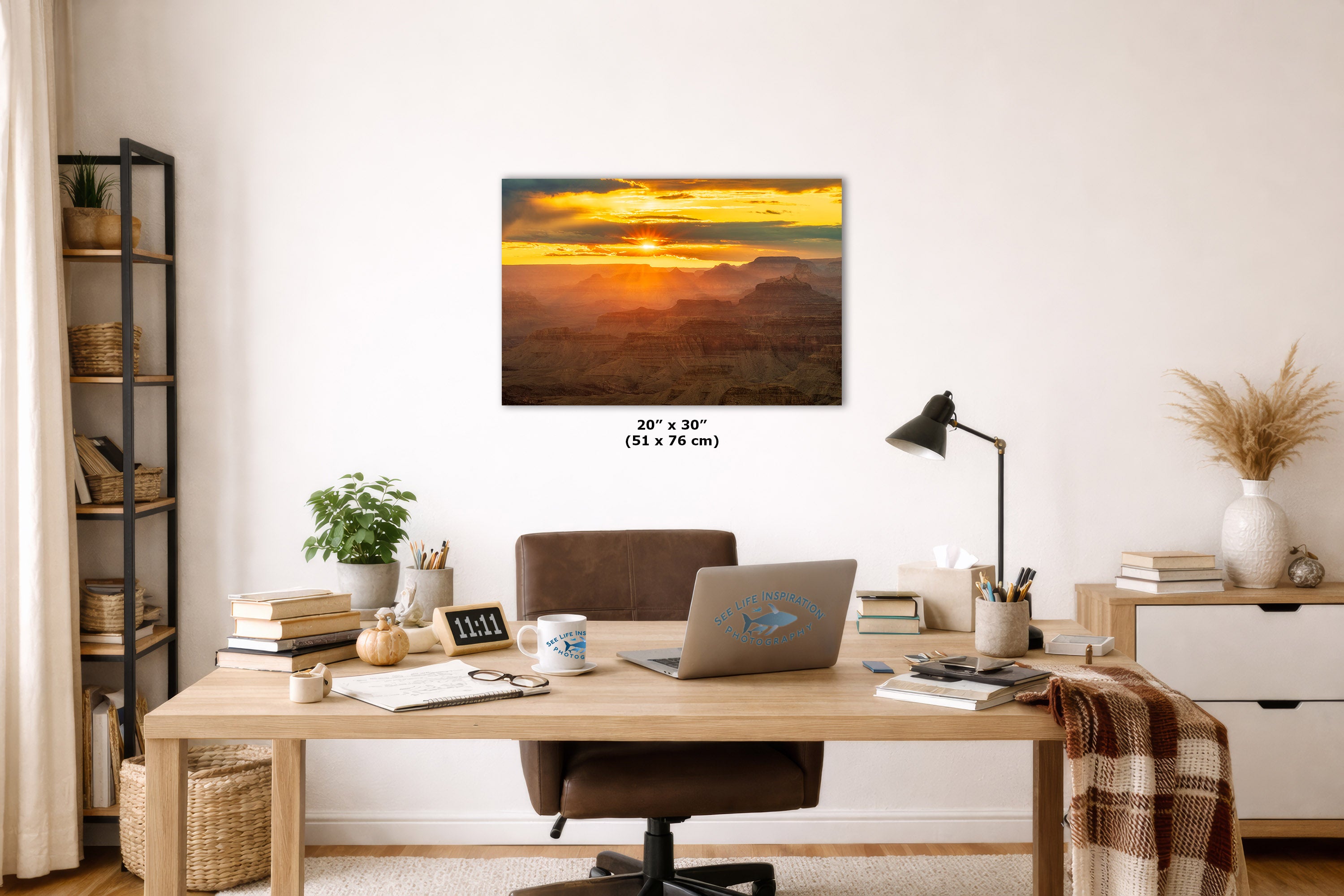 A 20 x 30 inch canvas wall art print depicting a golden sunset over a mountain landscape, displayed in a modern, well-lit home office setting above a wooden desk.