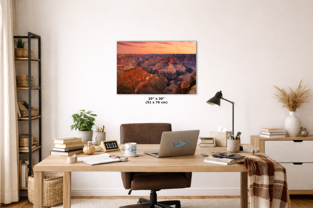 A wall art print showing a Grand Canyon landscape with warm sunset tones, displayed above a wooden desk in a styled home office. The print includes size text reading 20 x 30 cm.