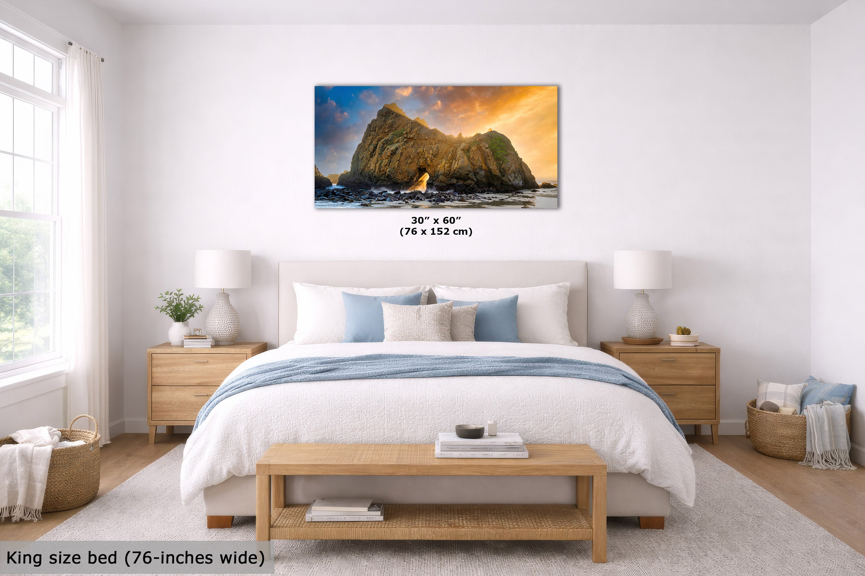 A framed wall art print showing a rocky coastal scene with warm sunset light is displayed above a neatly made bed in a bright, modern bedroom. The print includes size text reading 30" x 60" (76 x 152 cm), and the room scene also notes a king size bed 76-inches wide.