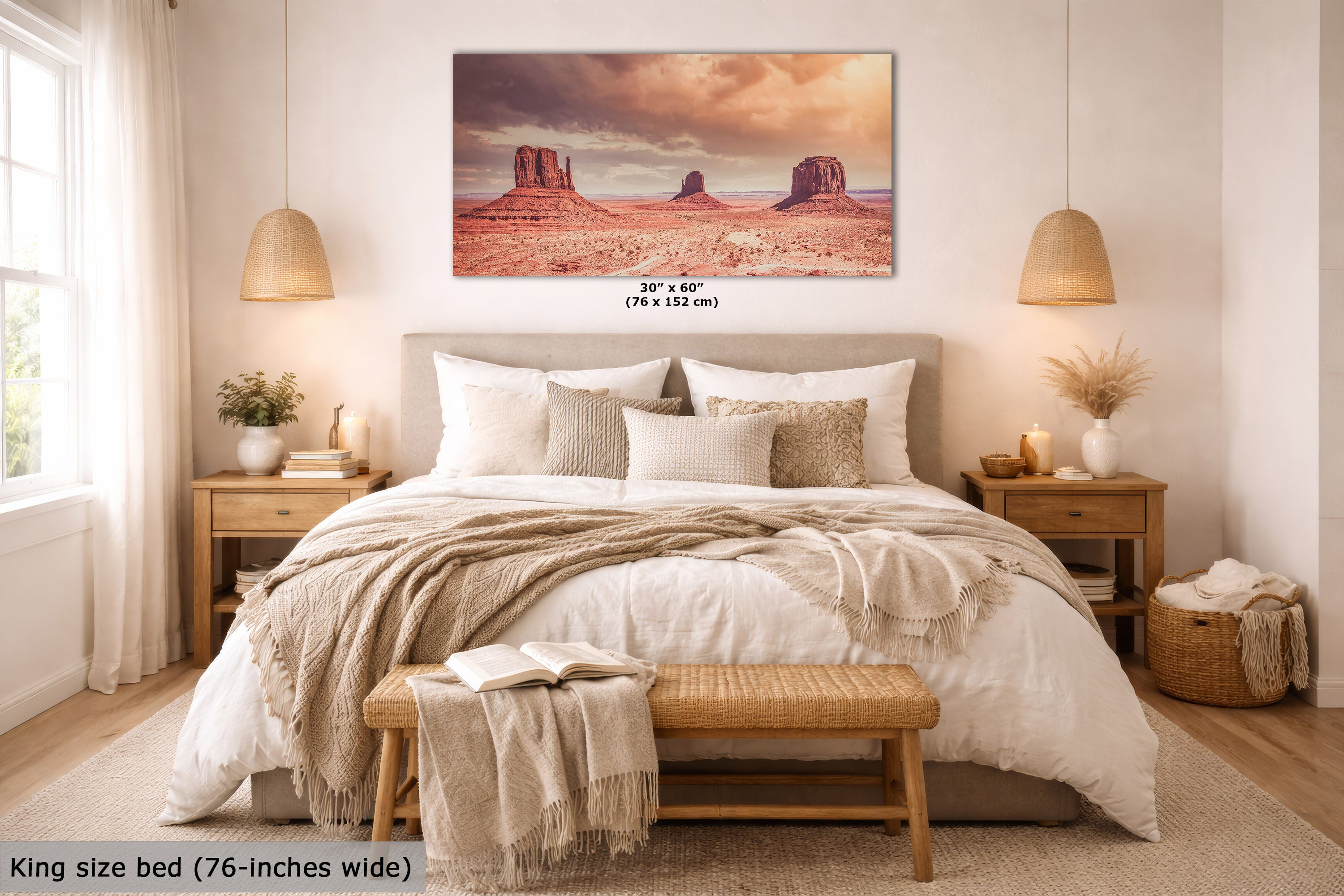 A wall art print depicting Monument Valley under a dramatic sunset sky, displayed above a neatly made bed in a warm, modern bedroom. The print includes size text indicating 30 x 60 inches (76 x 152 cm).