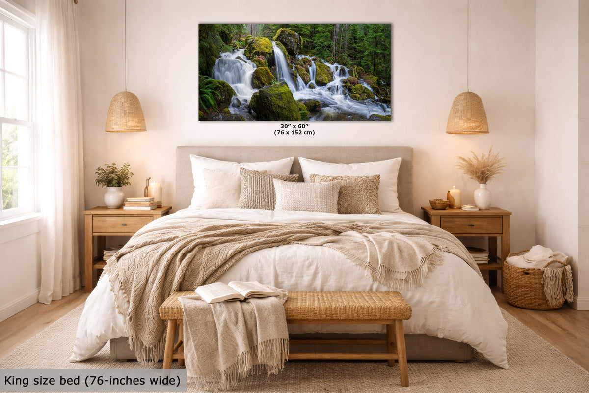 An Oregon cascading waterfall print of a lush green forest waterfall is displayed above a neatly made king-size bed in a warm, modern bedroom. The print includes size text indicating 30 x 60 inches (76 x 152 cm), and a text overlay at the bottom left states 'King size bed (76-inches wide)'.