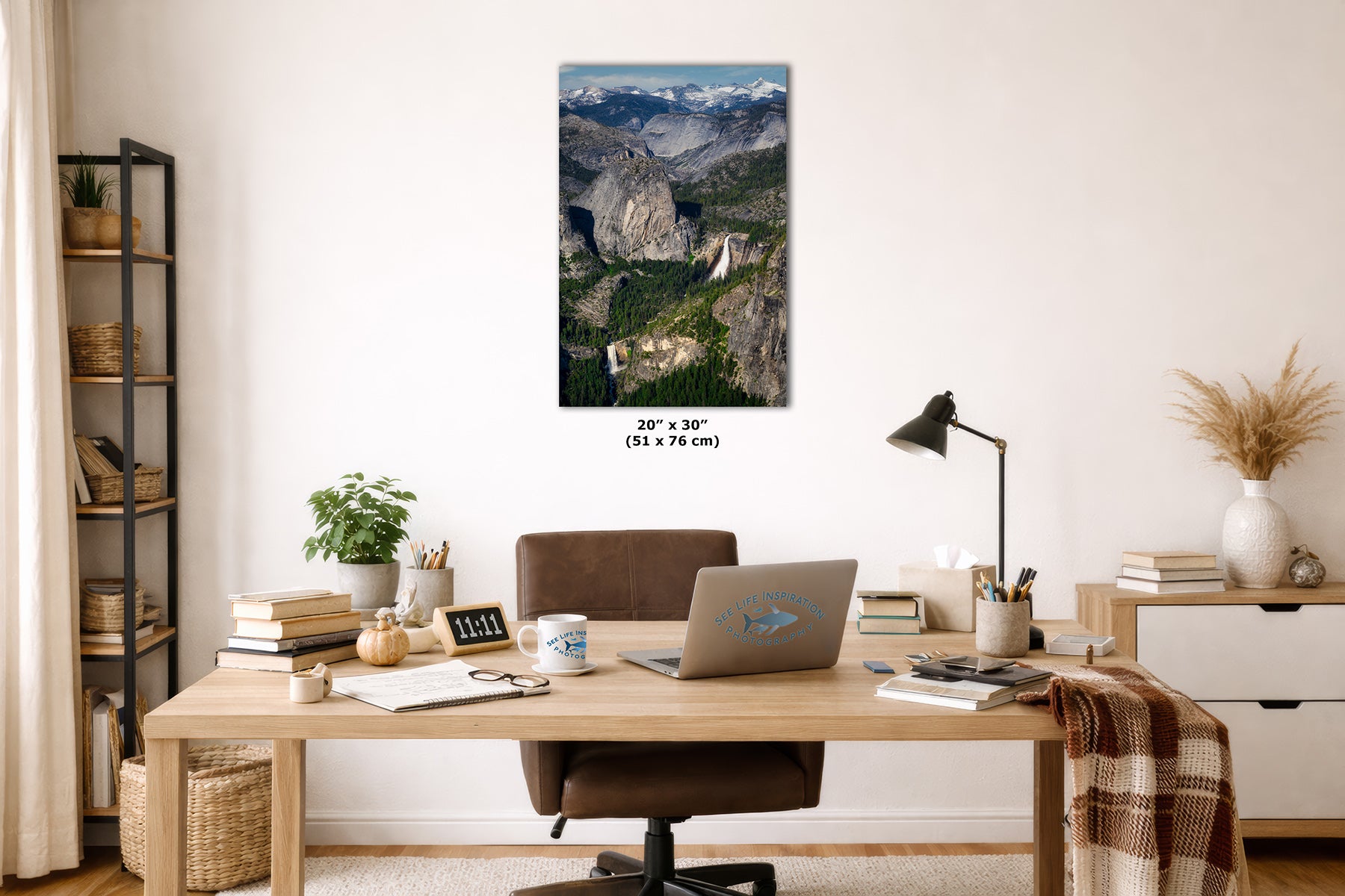 A Yosemite wall art print depicting a mountain landscape with the Nevada and Vernal waterfalls is displayed above a wooden desk in a styled home office. The print includes size text reading 24 x 30 in (51 x 76 cm) below it.