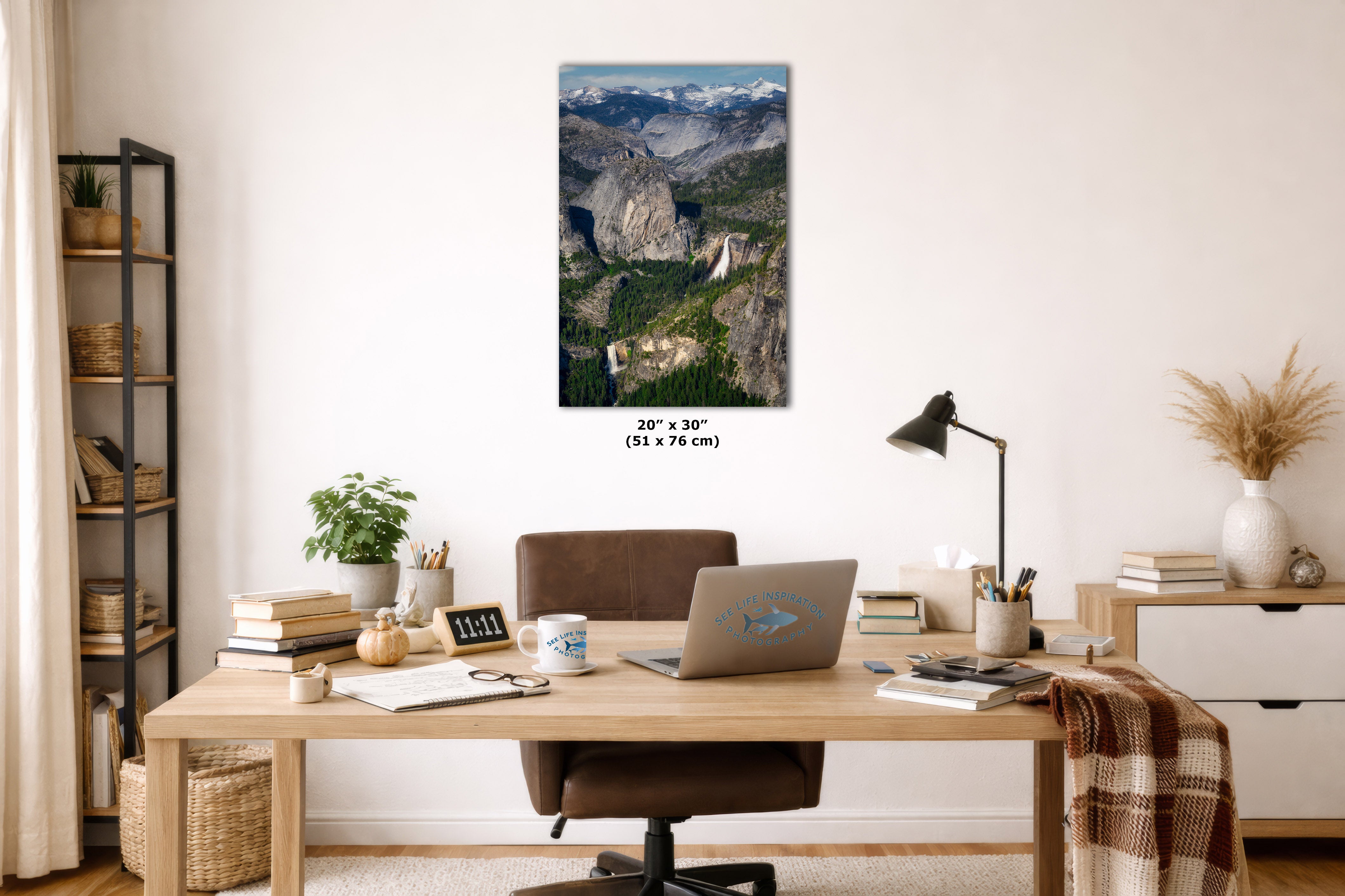 A wall art print showing a mountain landscape with a waterfall is displayed above a wooden desk in a styled home office. The print includes size text reading 24 x 30 in (51 x 76 cm) below it.