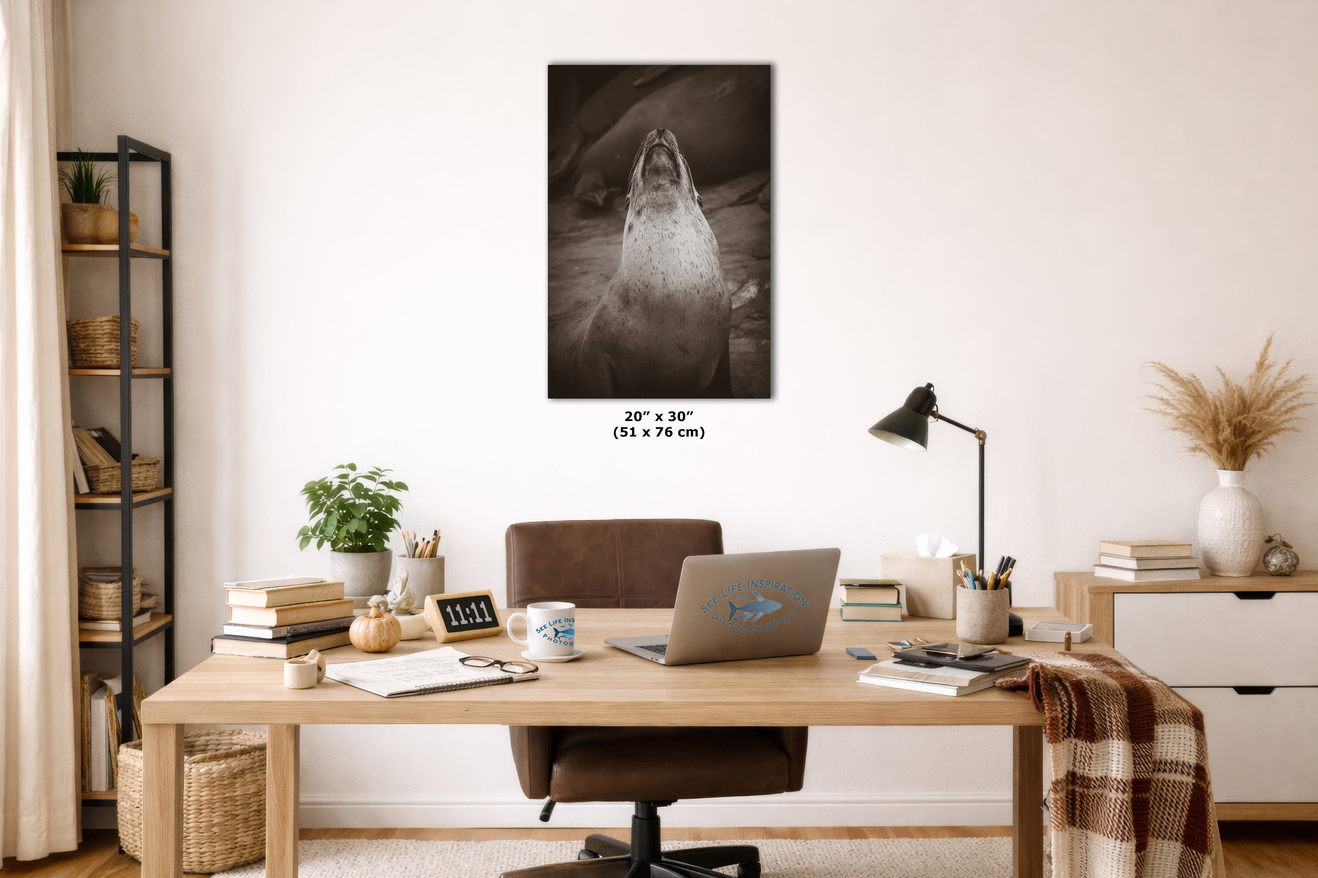 A black and white shark wall art print displayed in a modern home office setting above a wooden desk with a laptop, lamp, and other office accessories.