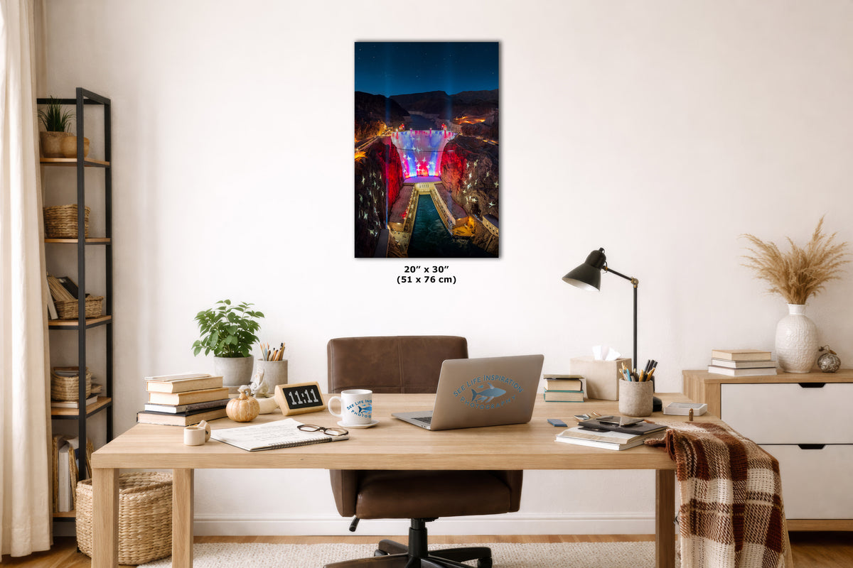 A wall art print showing a colorful city bridge at night hangs above a wooden desk in a styled home office. The print is labeled 20 x 30 inches (51 x 76 cm) and is shown in a bright, modern room setting with a desk, laptop, lamp, and shelving.