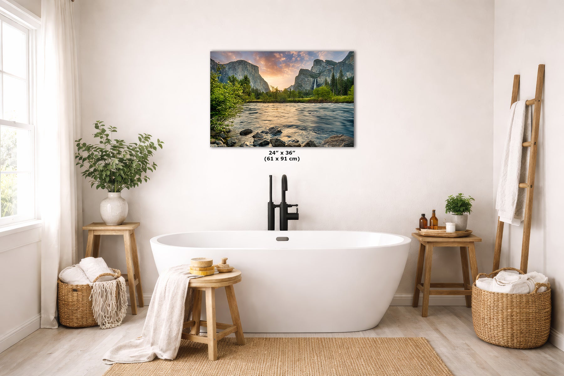 A framed wall art print showing a scenic mountain landscape from Yosemite National Park at sunrise hangs above a white freestanding bathtub in a bright, styled bathroom. The print includes size text reading 24 x 36 inches.