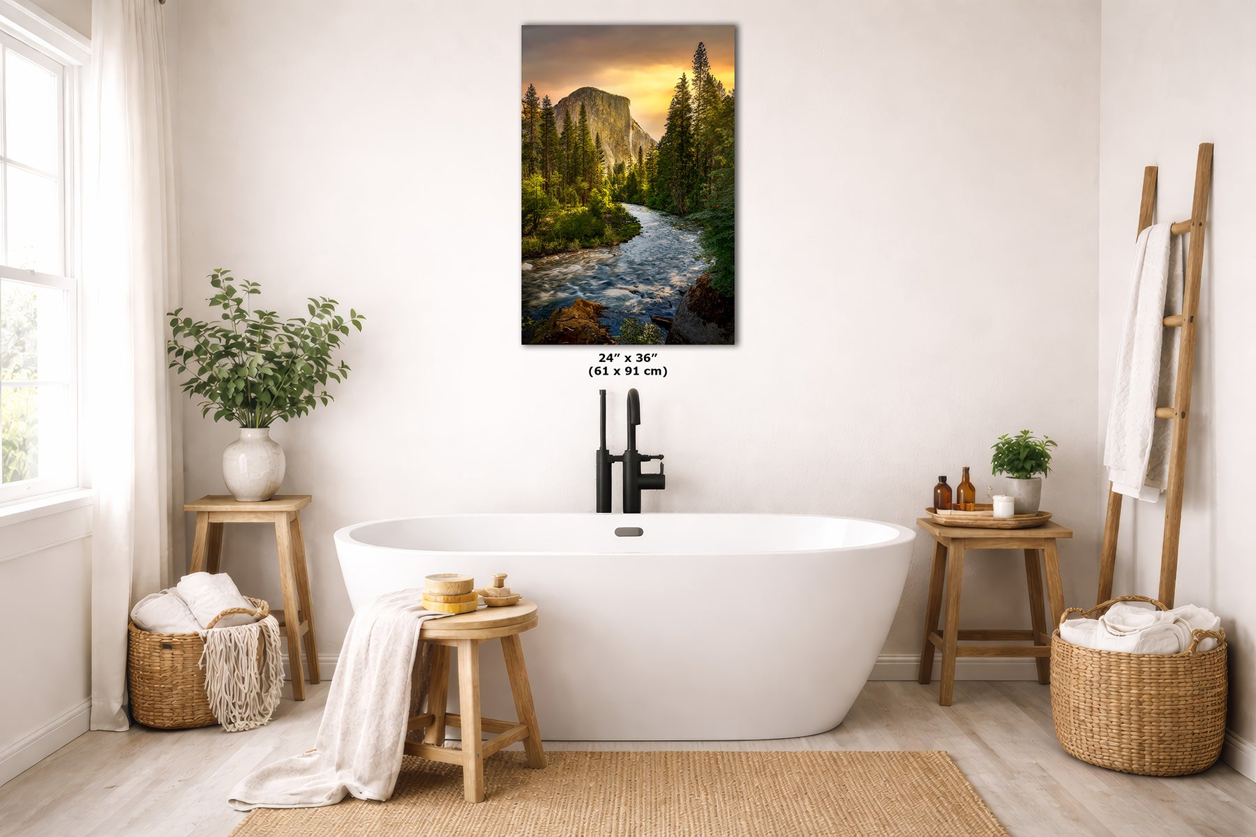 A vertical wall art print of a Yosemite landscape with El Capitan mountain and a glowing sunset, displayed above a white freestanding bathtub in a bright, neutral bathroom setting.