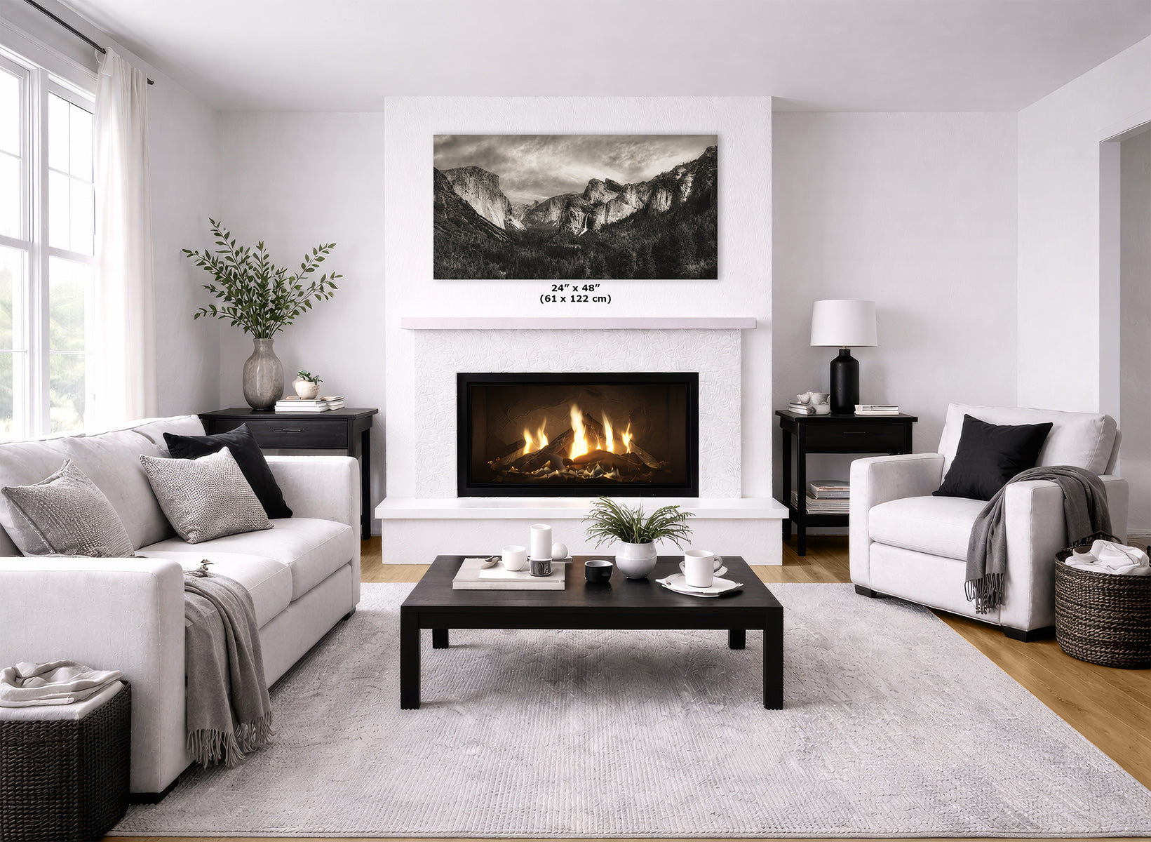 A modern living room featuring a white fireplace, a large black-and-white mountain landscape print of Yosemite Valley above it, a white sofa, a white armchair, and a dark wood coffee table on a light gray rug.