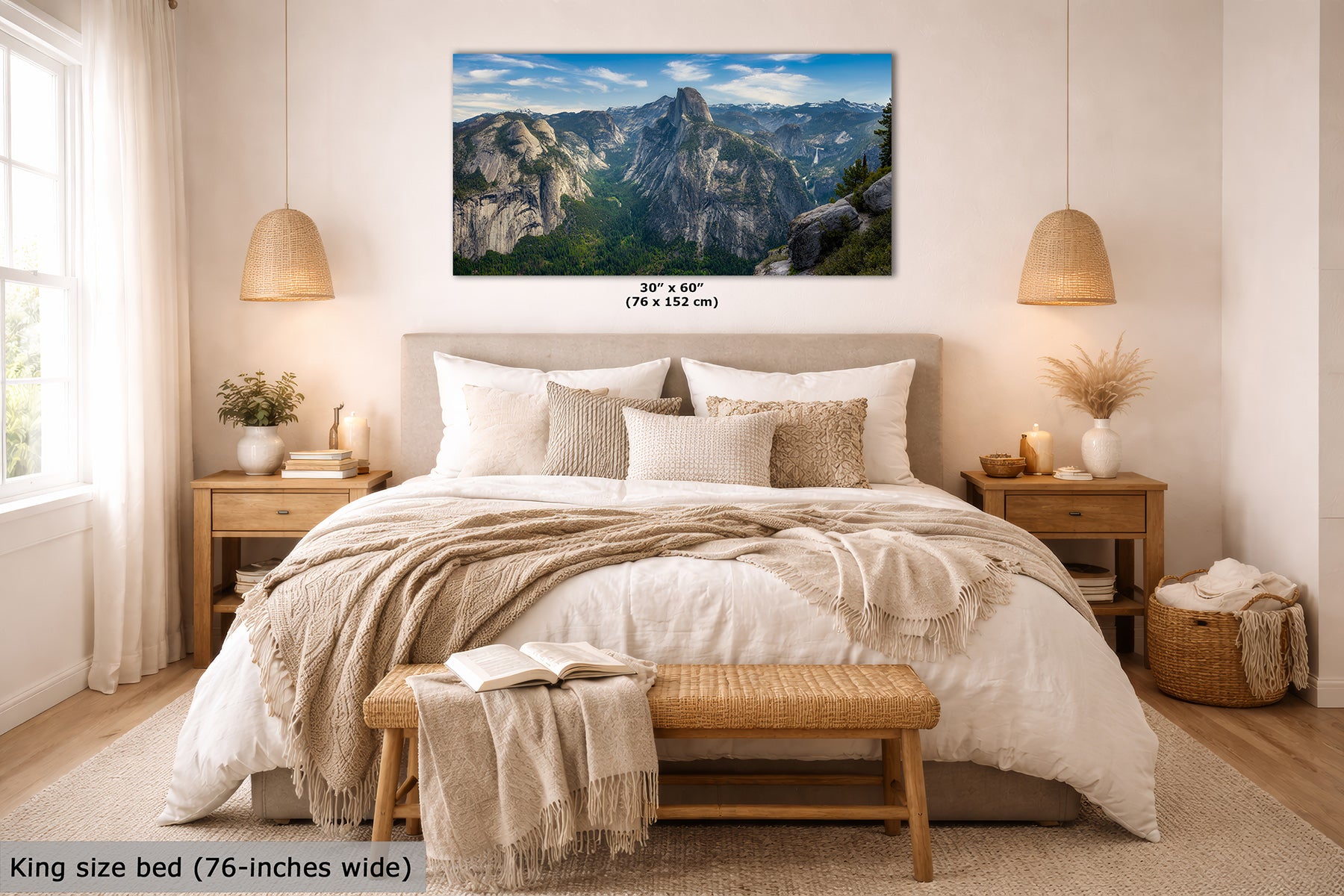 A framed mountain landscape wall art print displayed above a neatly made bed in a bright, modern bedroom. The print shows rocky peaks under a blue sky, with size text below it reading 30" x 60" (76 x 152 cm).