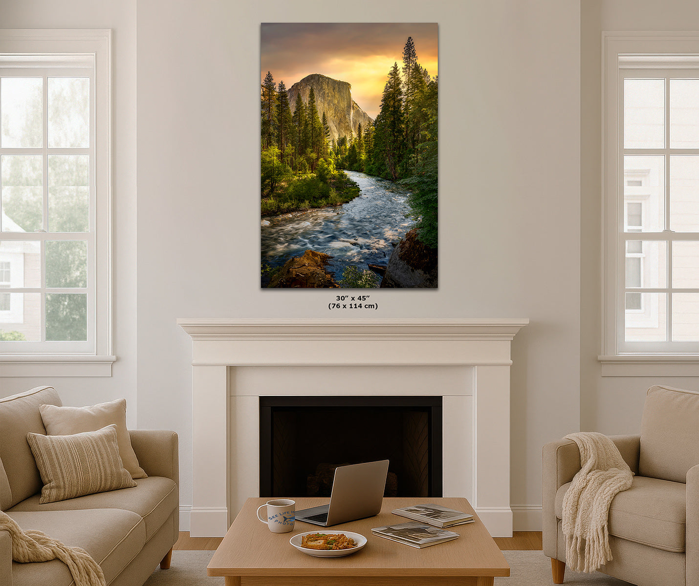 A vertical Yosemite wall art print depicting a scenic landscape of a rushing Merced River in a forest with El Capitan mountain and a golden sunset, displayed above a white fireplace mantel in a modern living room setting.