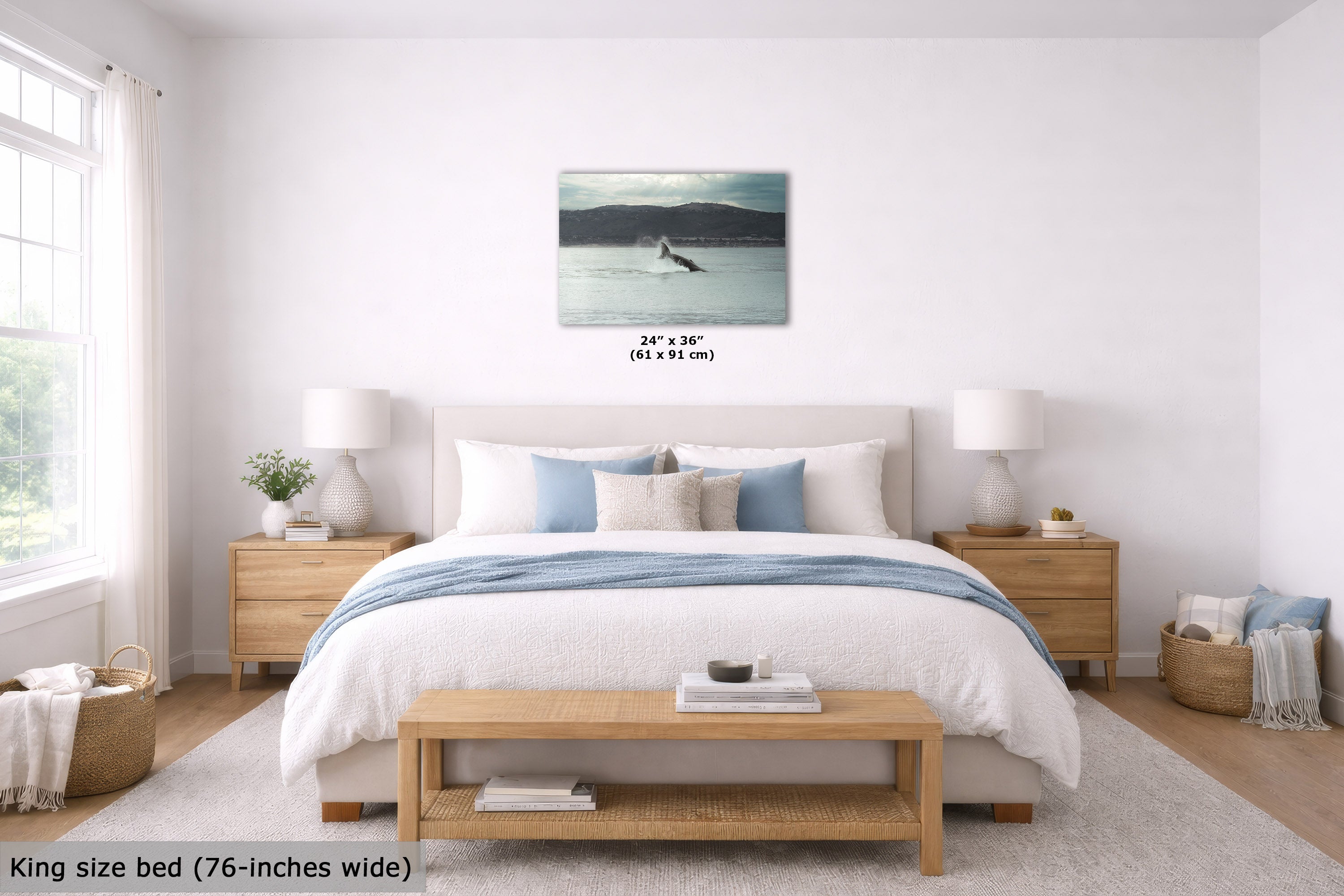 A wall art print showing a calm lake or river scene with a lone figure on a paddleboard, displayed above a neatly made bed in a bright, modern bedroom. The print includes size text reading 24" x 36" (61 x 91 cm).