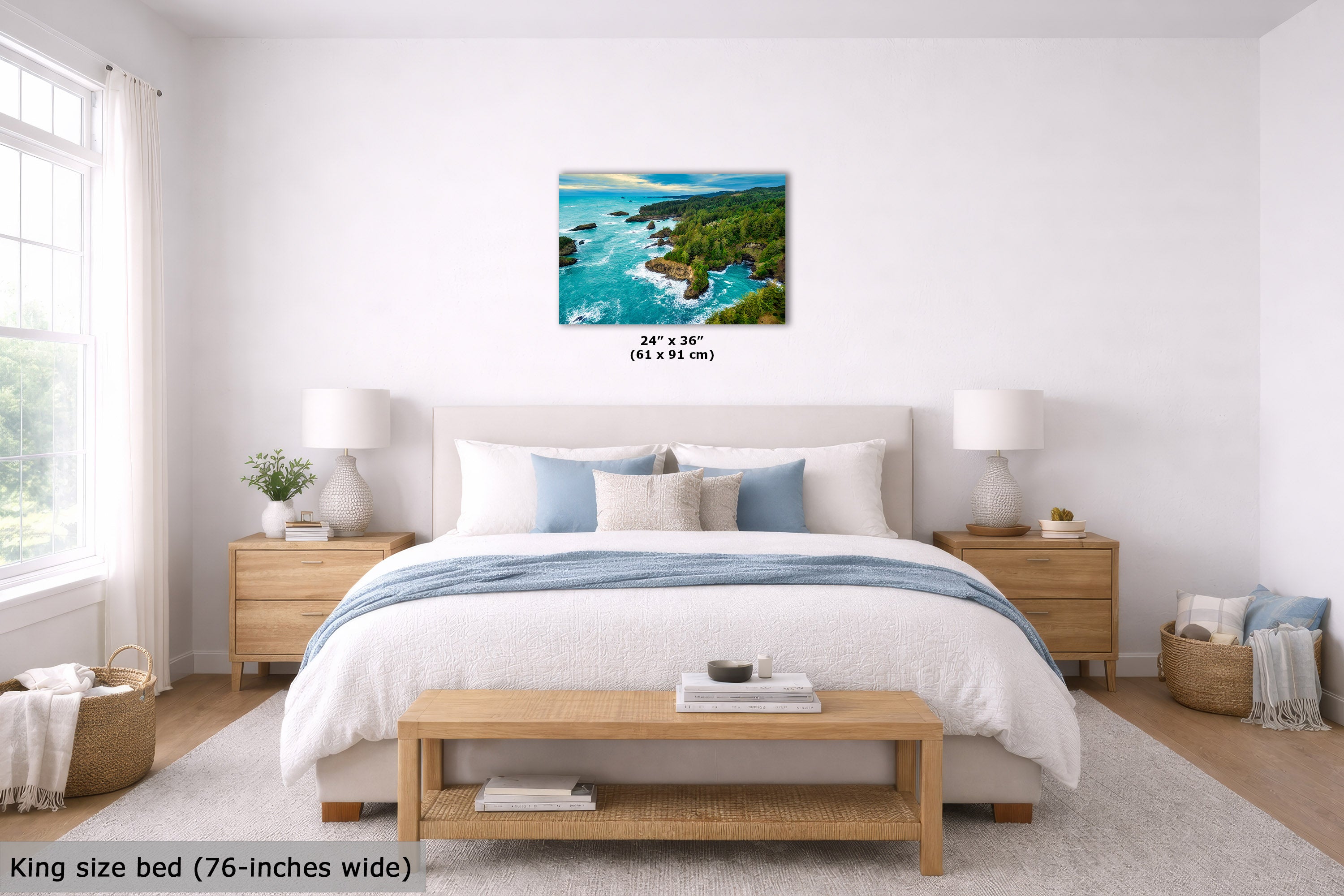 A coastal landscape wall art print hangs above a neatly made bed in a bright, modern bedroom. The artwork shows turquoise ocean water, rocky shoreline, and green cliffs.