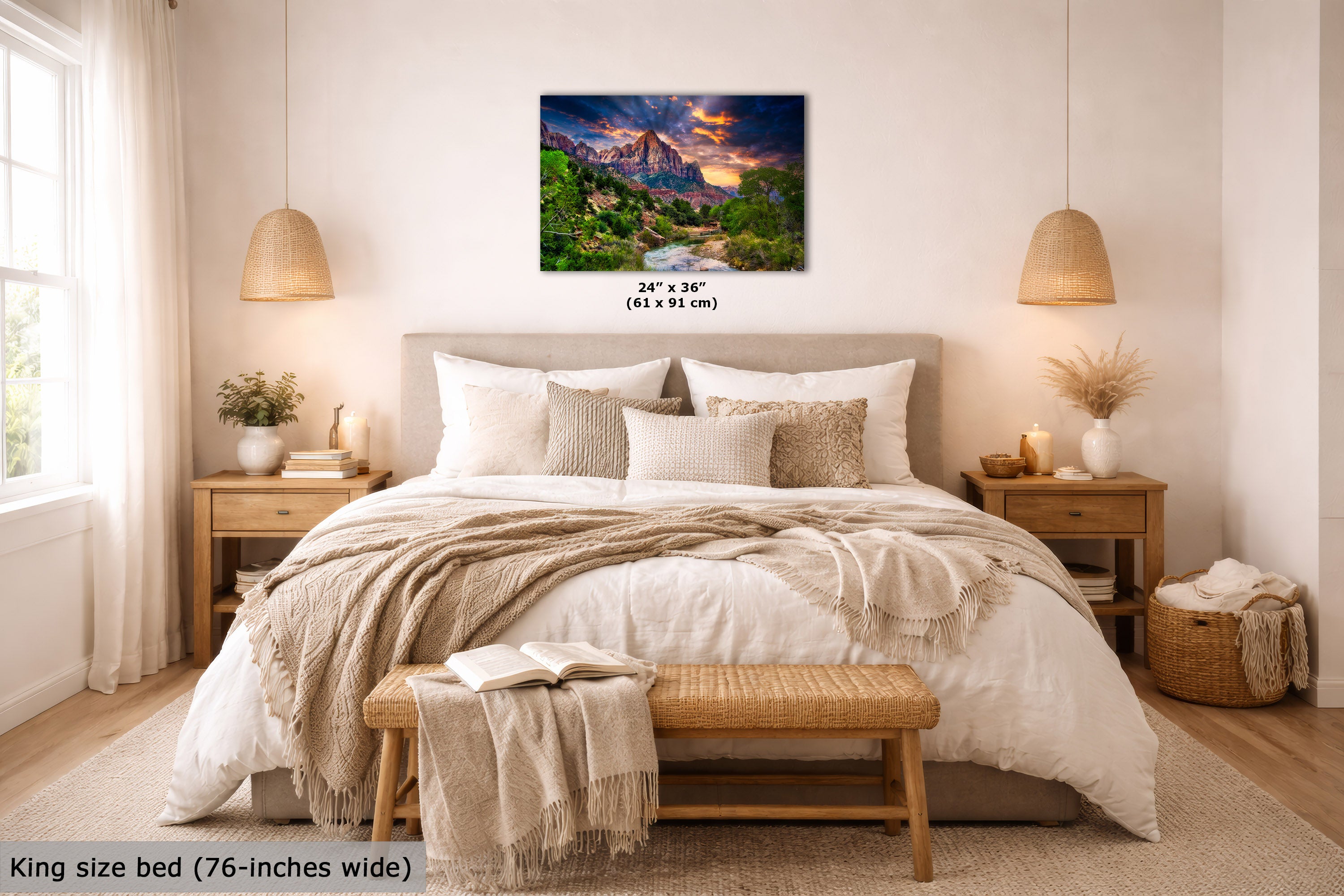 A wall art print showing a colorful mountain landscape with a river and glowing sunset, displayed above a neatly made bed in a bright, modern bedroom. The print includes size text reading 24 x 36" (61 x 91 cm), and the scene is framed by matching bedside tables, lamps, pillows, and a bench.