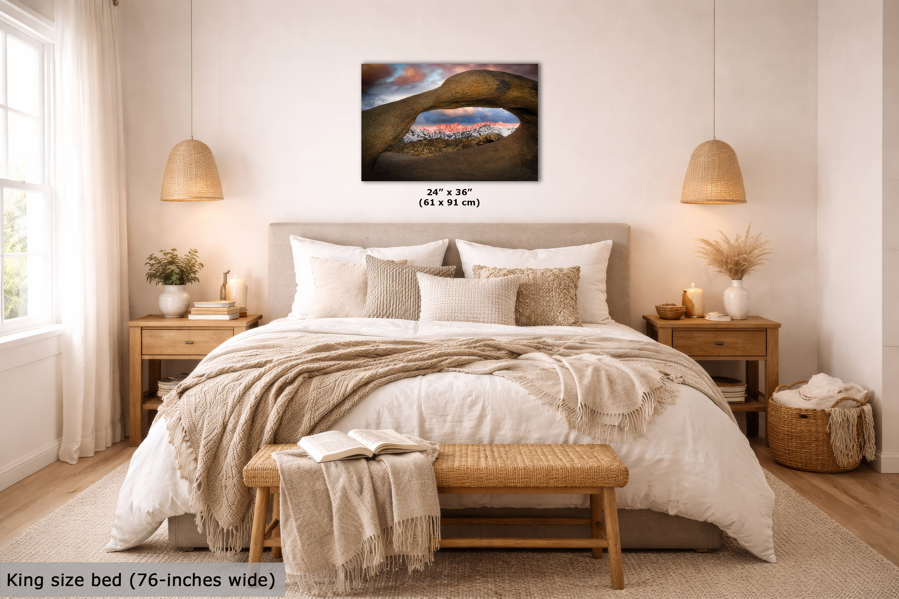 A wall art print showing a desert landscape with a large arch and colorful sky, displayed above a neatly made bed in a bright, modern bedroom. The print includes size text reading 24 x 36 inches (61 x 91 cm).