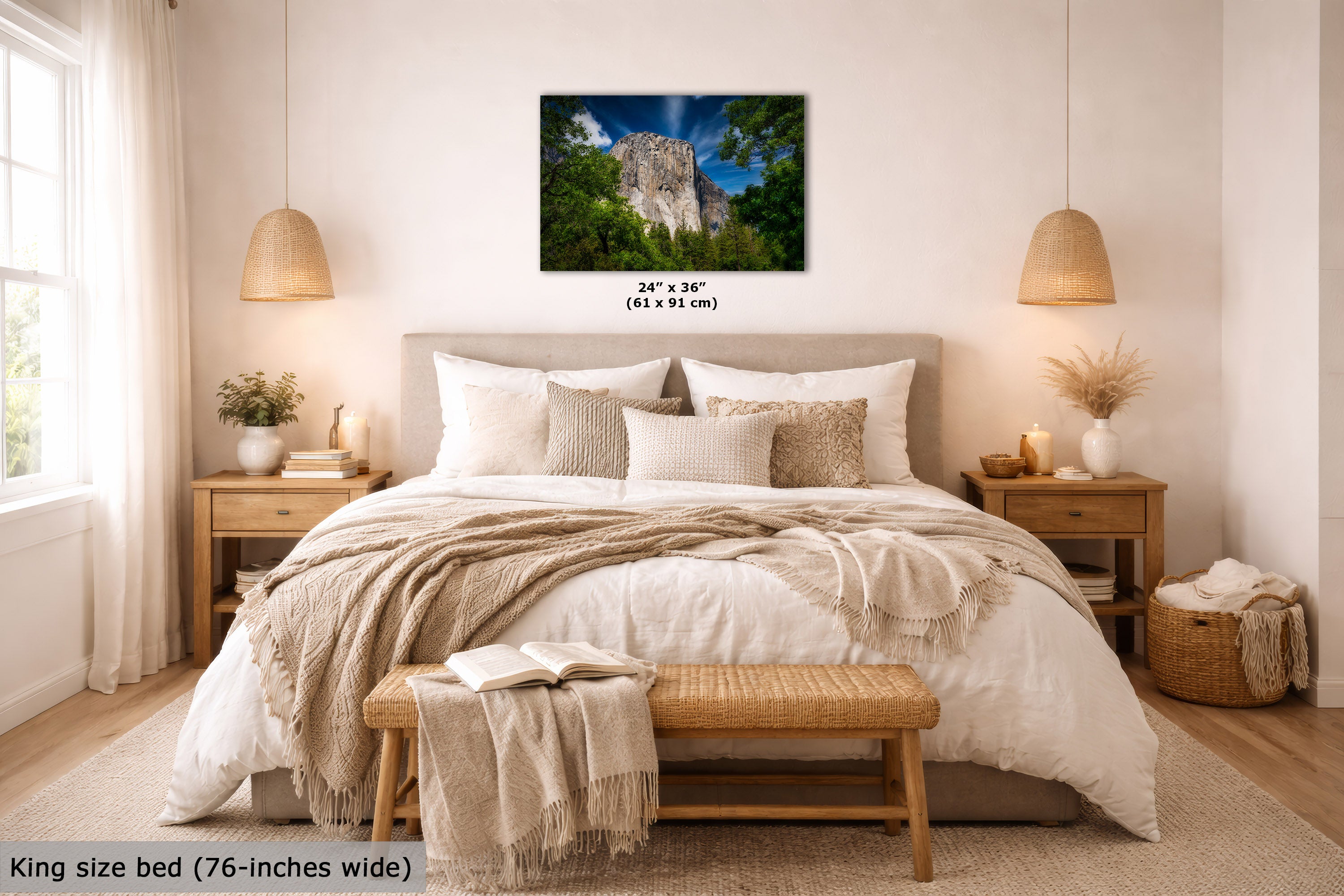 A wall art print showing a rocky cliff surrounded by green trees under a blue sky, displayed above a neatly made bed in a bright, modern bedroom. The print includes size text reading 24 x 36 inches, and the image also notes the bed is king size (76-inches wide).
