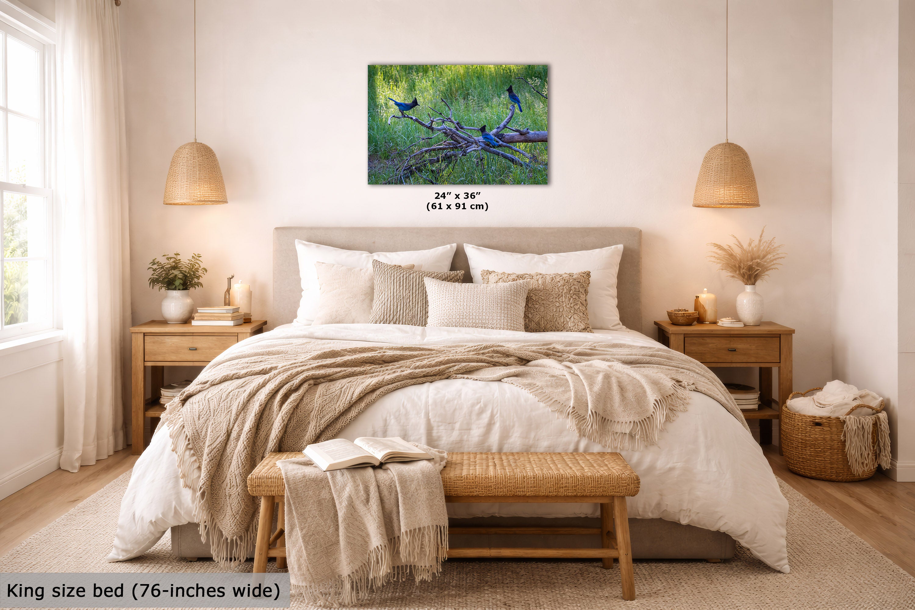 A wall art print showing blue birds perched on a branch in a grassy green landscape, displayed above a neatly made bed in a bright, modern bedroom. The print includes size text reading 24" x 36" (61 x 91 cm).