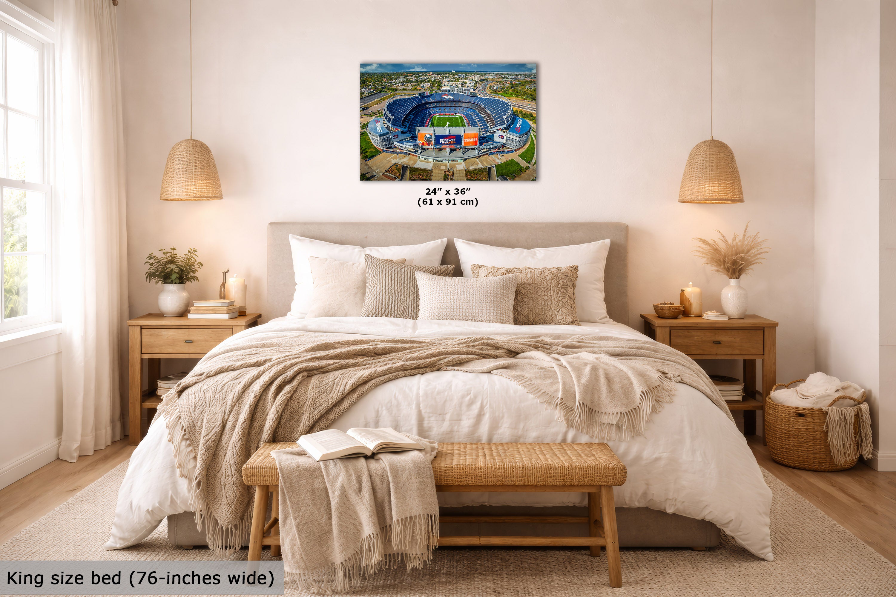 A wall art print showing an aerial view of a blue stadium, styled above a neatly made bed in a bright, modern bedroom. The print includes size text indicating 24 x 36 inches (61 x 91 cm), and the image has a text overlay at the bottom left stating 'King size bed (76-inches wide)'.