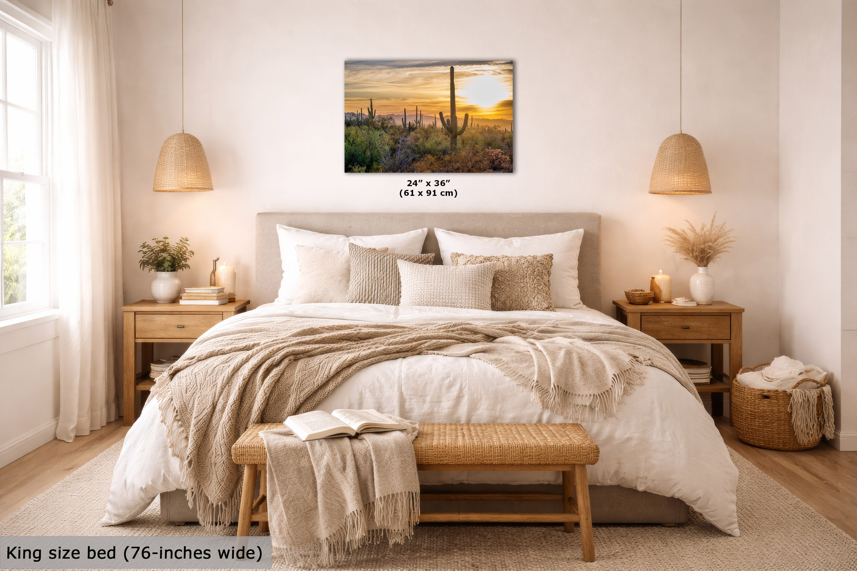 A wall art print showing a desert sunset with cacti is displayed above a neatly made bed in a bright, modern bedroom. The print includes size text reading 24 x 36 inches (61 x 91 cm), and the scene is labeled as a King size bed (76-inches wide) at the bottom left.
