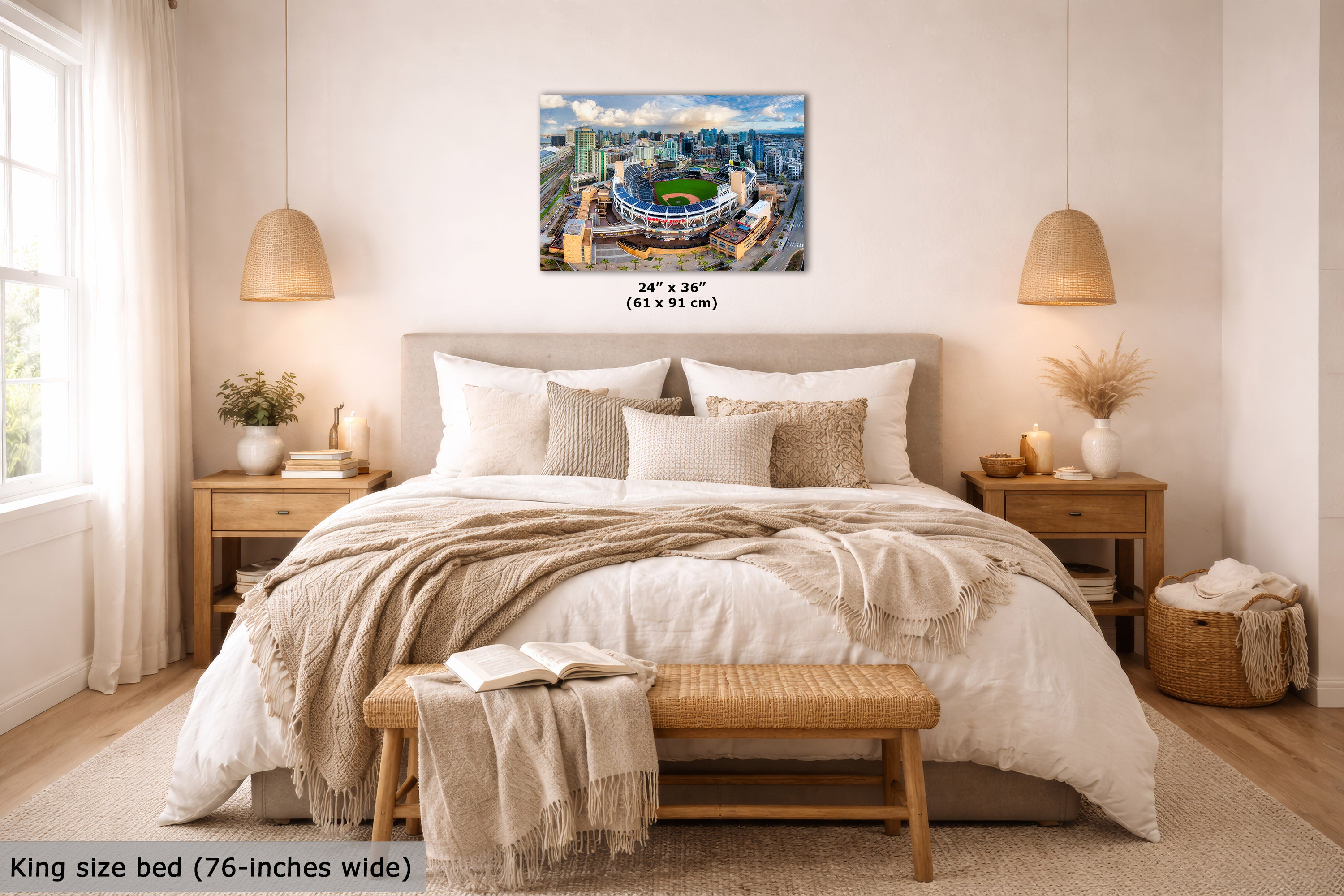 A wall art print showing a stadium cityscape is displayed above a neatly made bed in a bright, modern bedroom. The print includes size text reading 24 x 36 inches (61 x 91 cm), and the room scene includes a text overlay at the bottom left stating King size bed (76-inches wide).