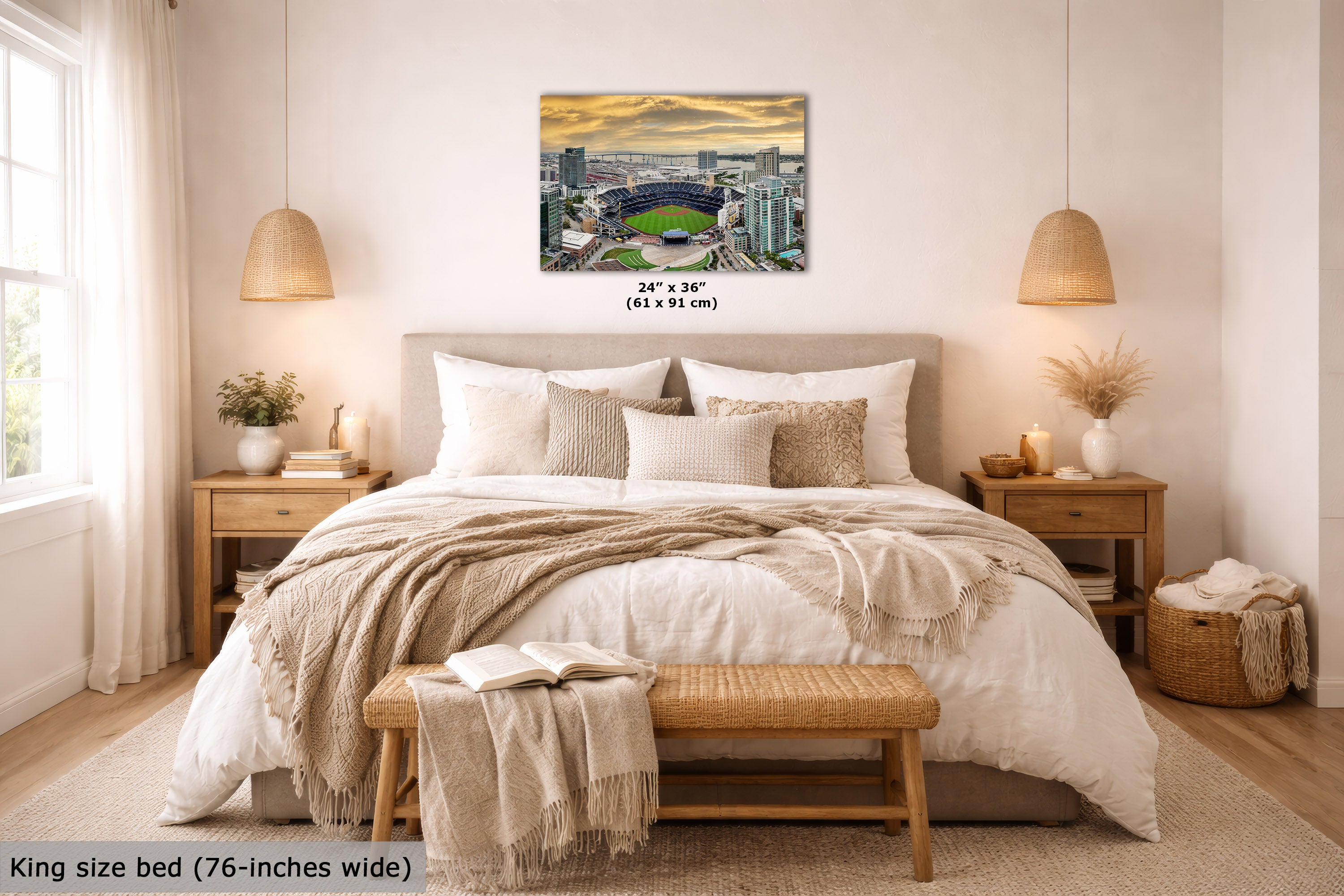 A wall art print showing a stadium scene with a dramatic sunset sky, displayed above a neatly made bed in a warm, modern bedroom. The print includes size text reading 24 x 36 inches (61 x 91 cm), and the image has a text overlay at the bottom left stating King size bed (76-inches wide).