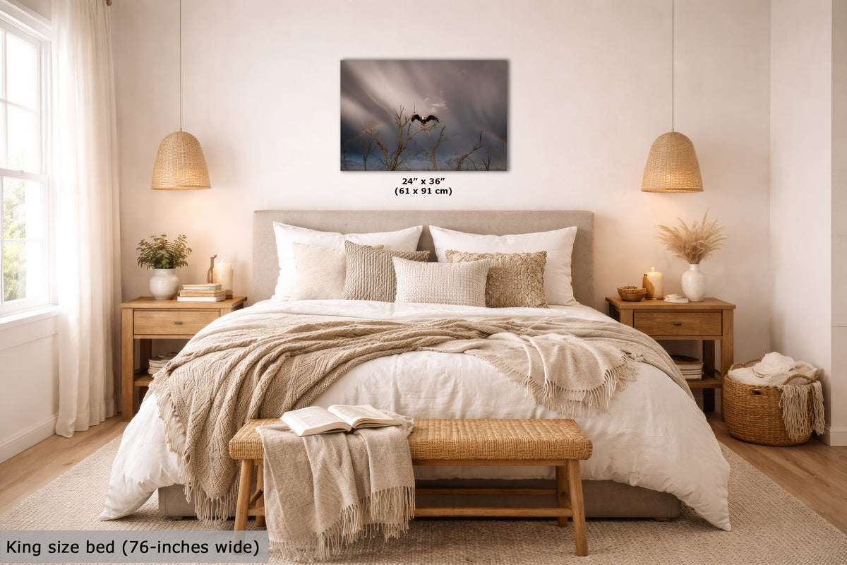 A wall art print showing a moody dark blue sky with two heart-shaped silhouettes, displayed above a neatly made bed in a warm, modern bedroom. The print includes size text reading 24" x 36" (61 x 91 cm).