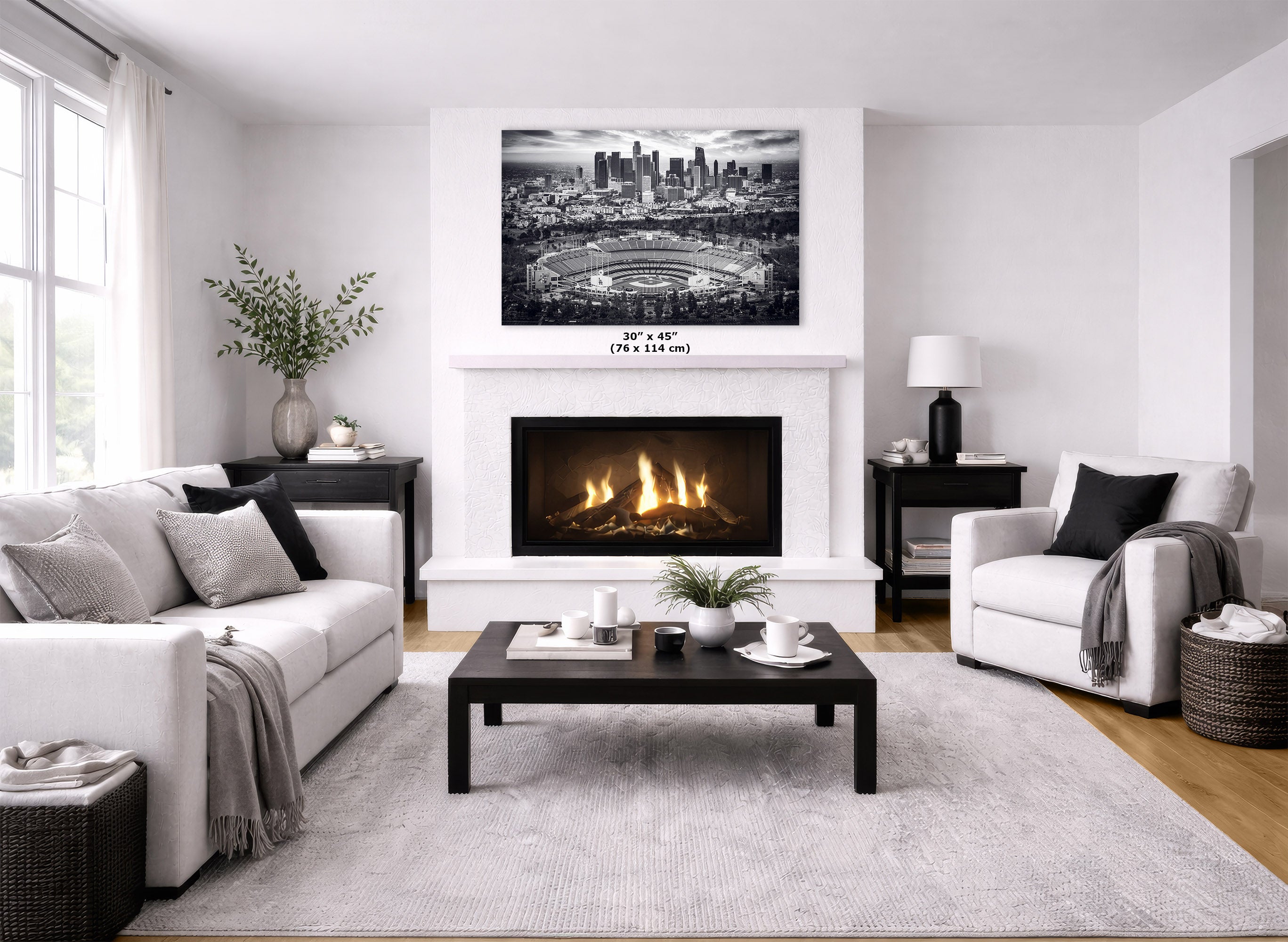 A black and white Los Angeles skyline wall art print displayed above a white fireplace in a modern, bright living room with a fireplace, sofas, and coffee table.