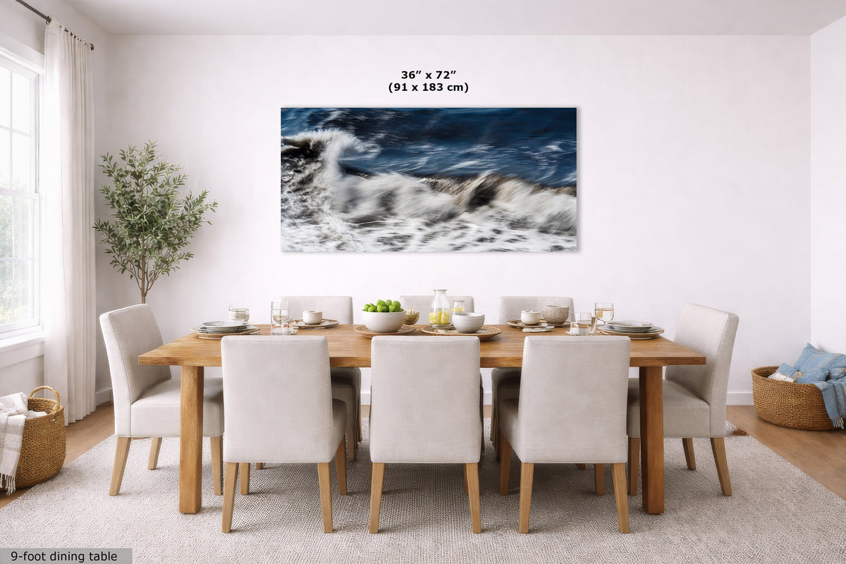 A large rectangular wall art print showing a dramatic ocean wave scene in deep blue and white tones, displayed above a wooden dining table with upholstered chairs in a bright dining room. Text at the top indicates the print size as 36 x 72 inches (91 x 183 cm).