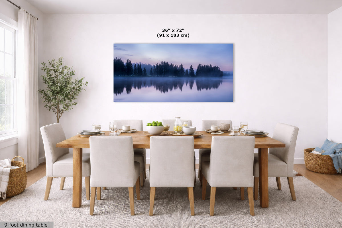 A large rectangular wall art print showing a misty forest lake at dusk, displayed above a wooden dining table with upholstered chairs in a bright dining room. Text above the print reads 36 x 72 in (91 x 183 cm).