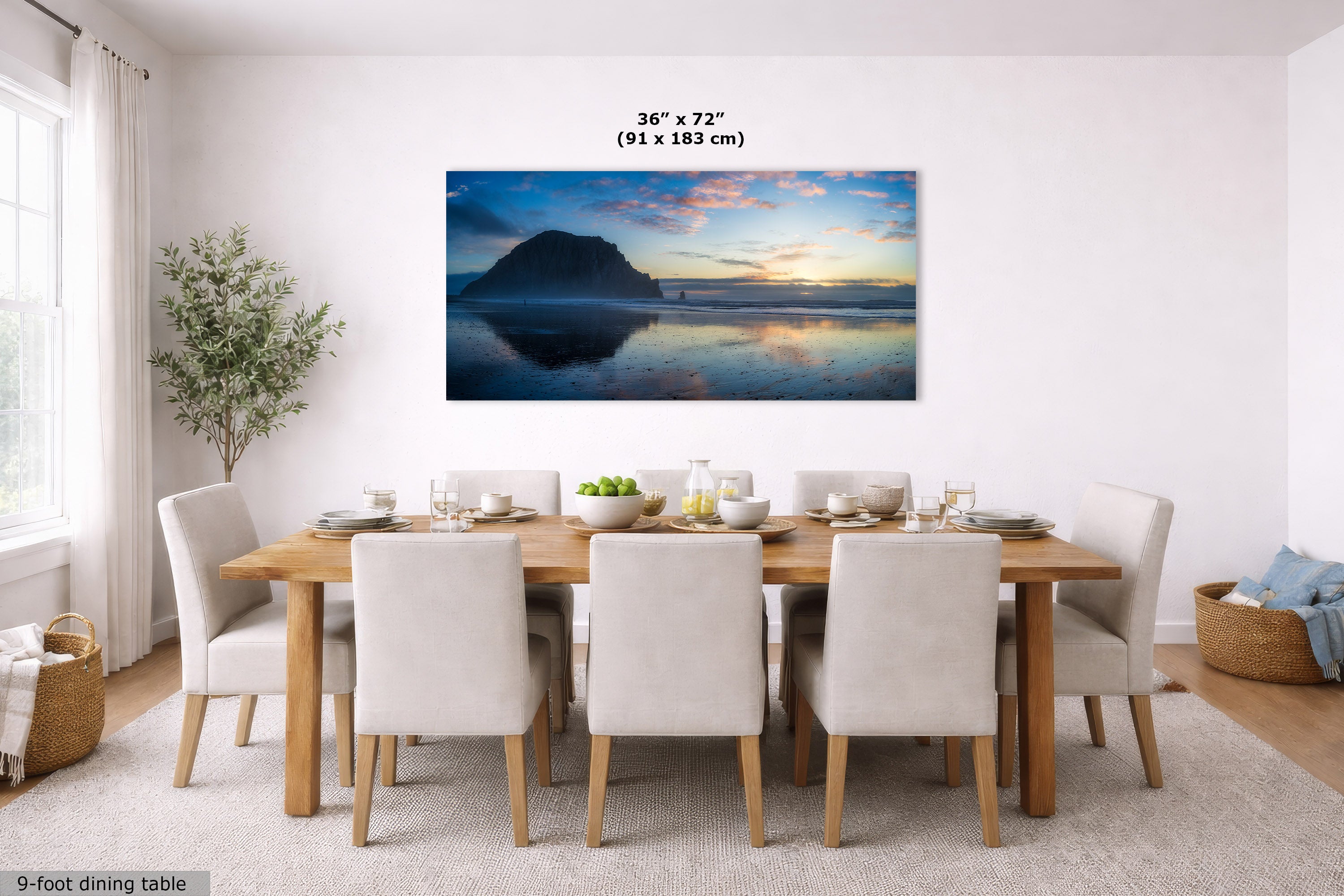 A large rectangular wall art print showing a mountain lake sunset hangs above a wooden dining table with upholstered chairs in a bright dining room. The print includes size text reading 36 x 72 inches (91 x 183 cm).