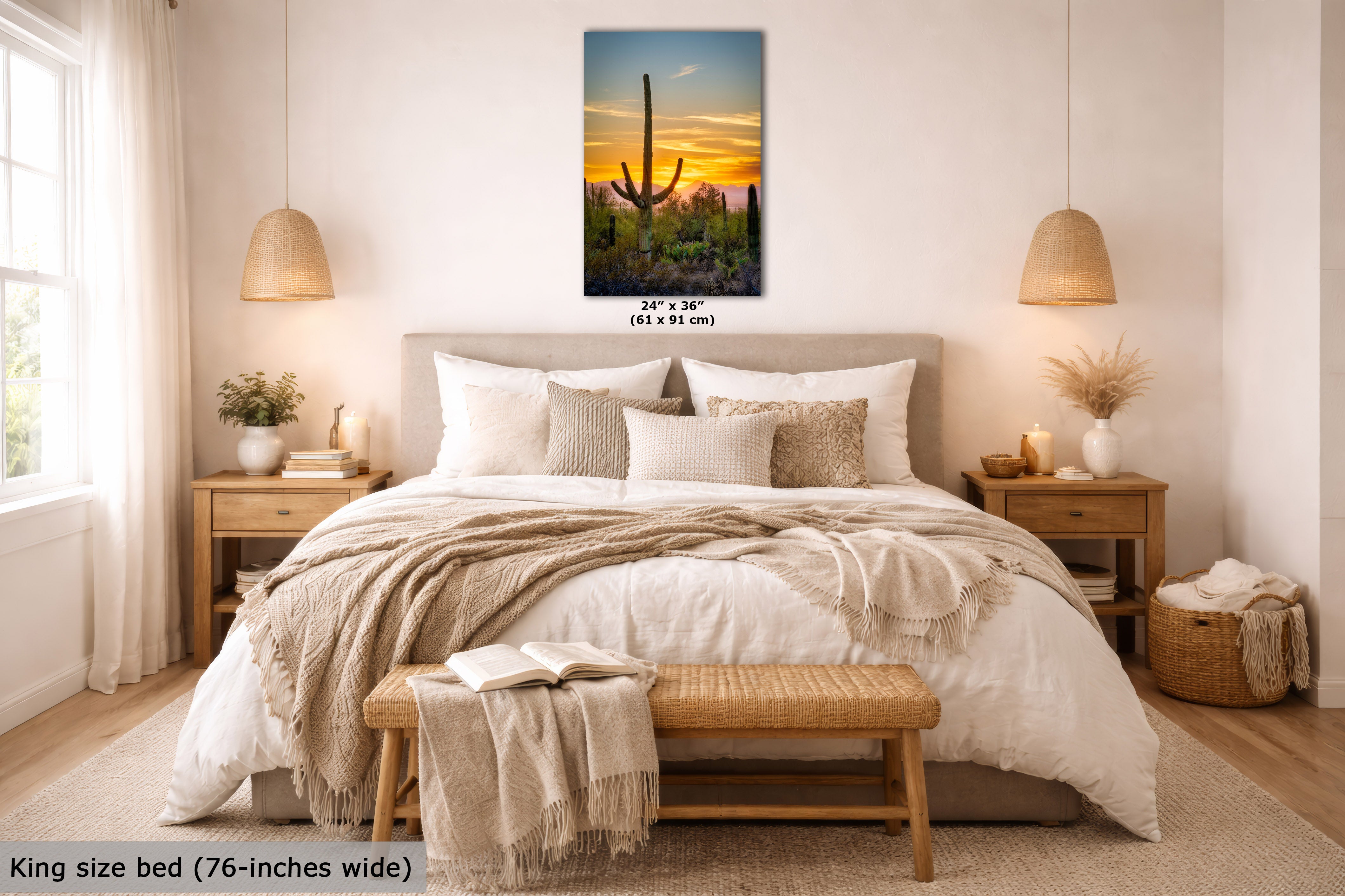 A framed vertical canvas print of a desert sunset with a saguaro cactus is displayed on a beige wall above a neatly made bed in a modern, well-lit bedroom. The text overlay indicates the dimensions of the print.